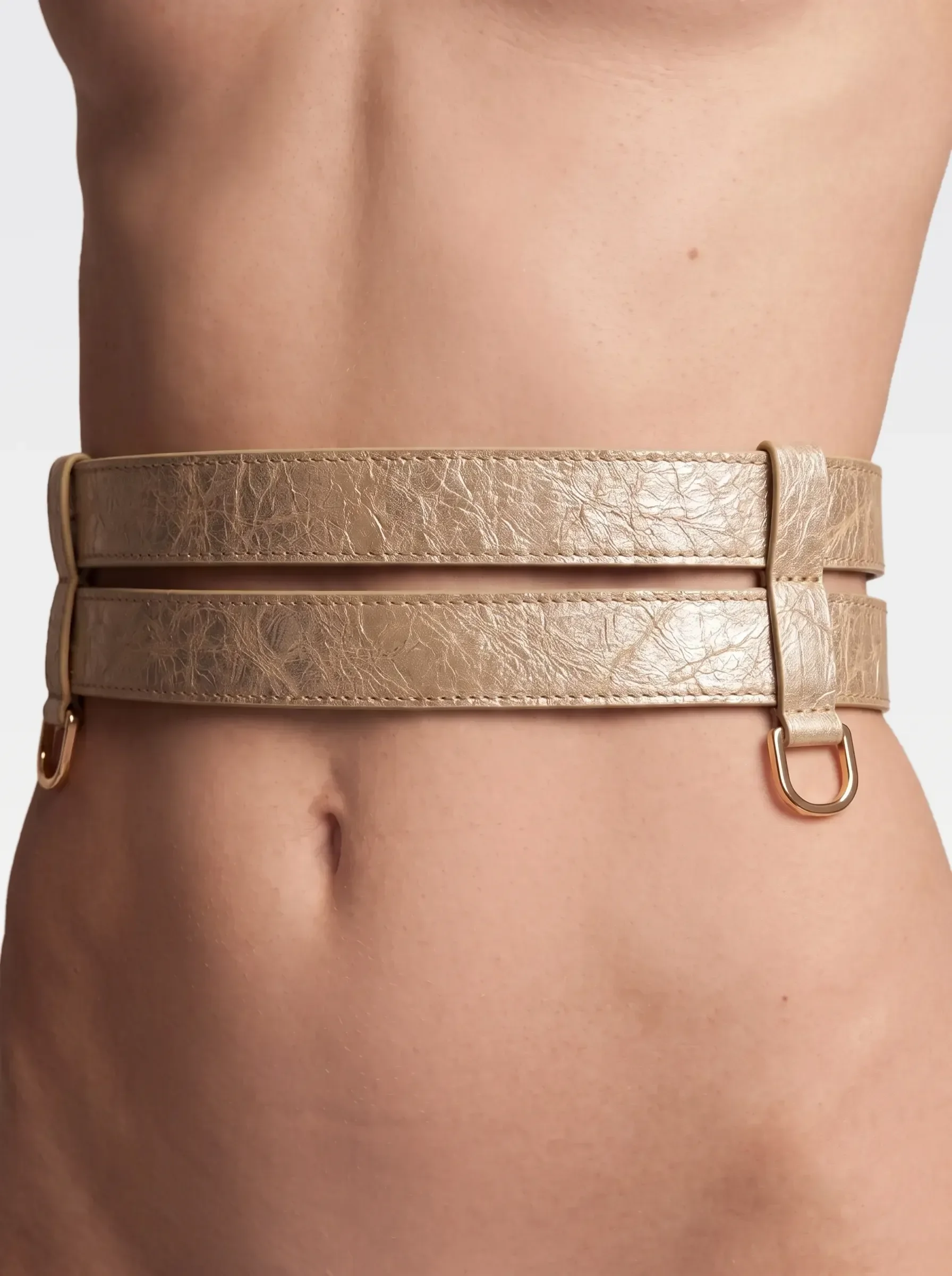 Sainte Sve Belt Laminated in gold laminated lambskin with 24K gold-plated brass D ring, worn at the waist, editorial image