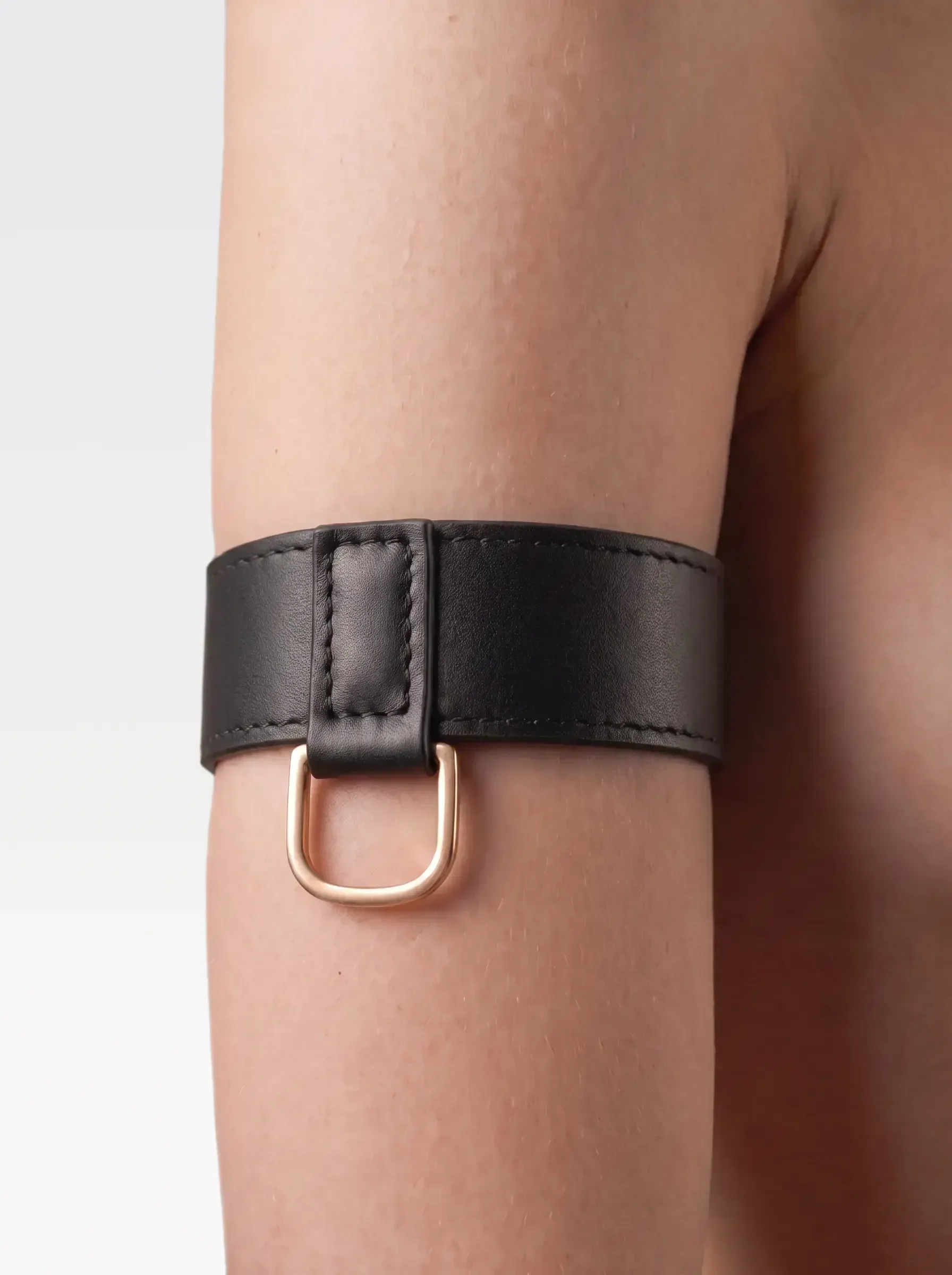 Sainte Sve Arm Bracelets Nappa in black nappa lambskin with a 24K gold-plated brass D ring, worn on the upper arm, editorial image