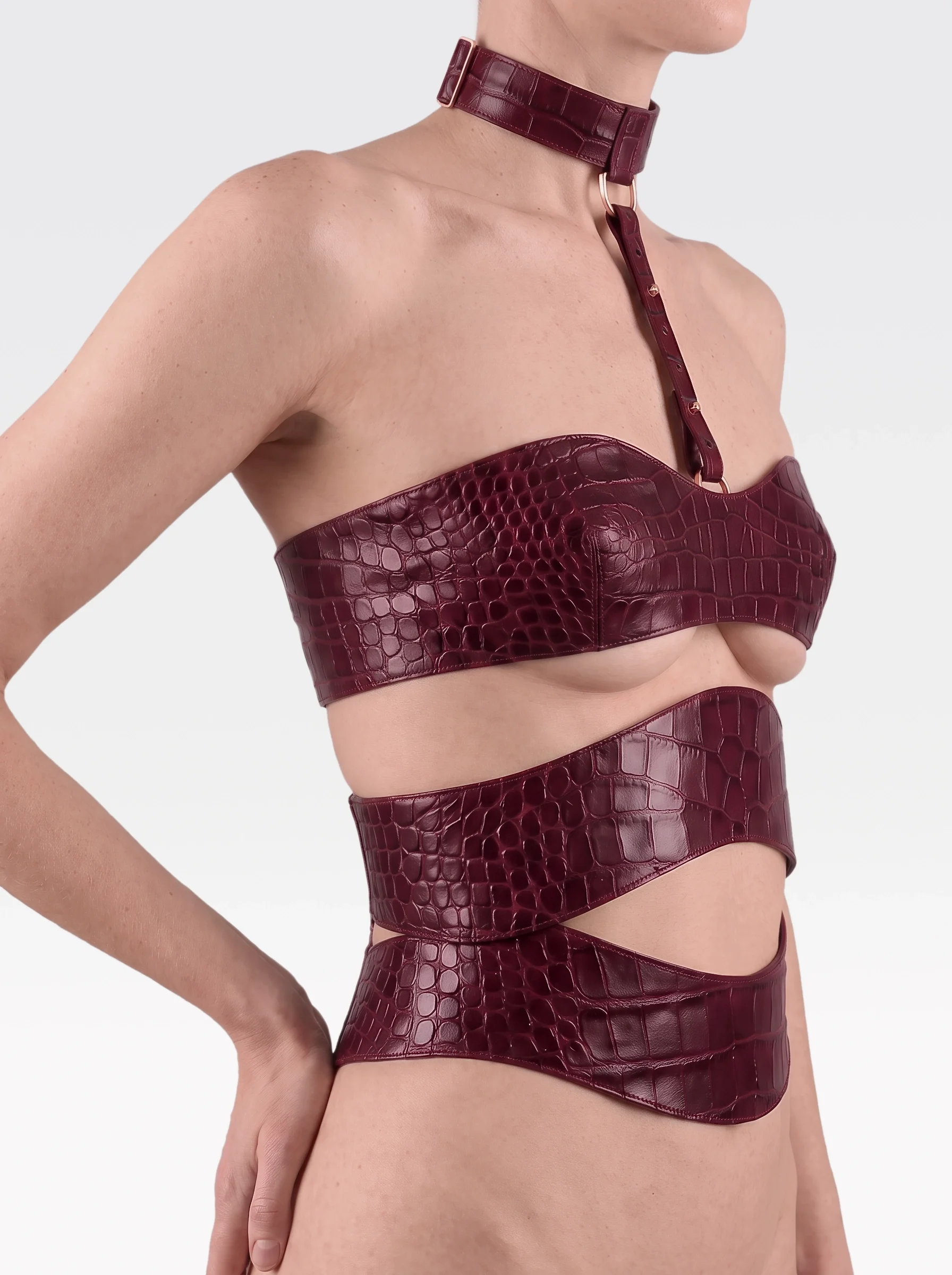 Sainte Sve V.N.V Croc in burgundy crocodile-embossed lambskin with burgundy elastic bands and zip, worn from neck to waist, side view, editorial image