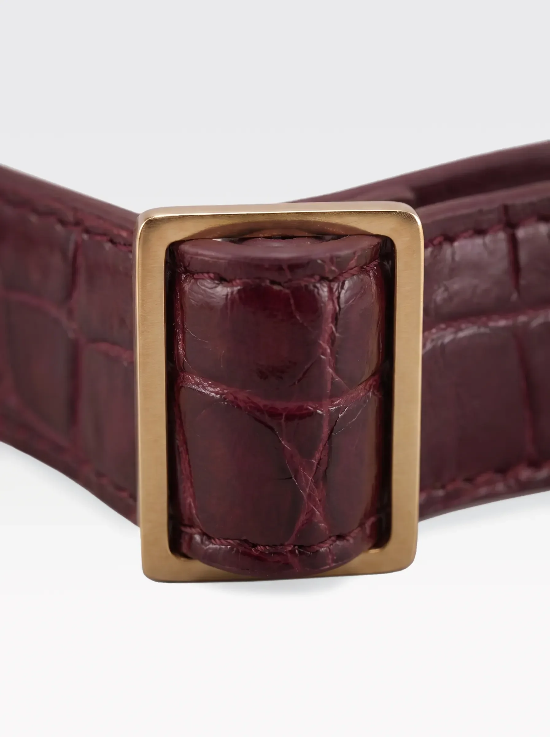 Close-up of the 24K gold-plated brass slider on the burgundy crocodile-embossed lambskin of a Sainte Sve Choker Croc