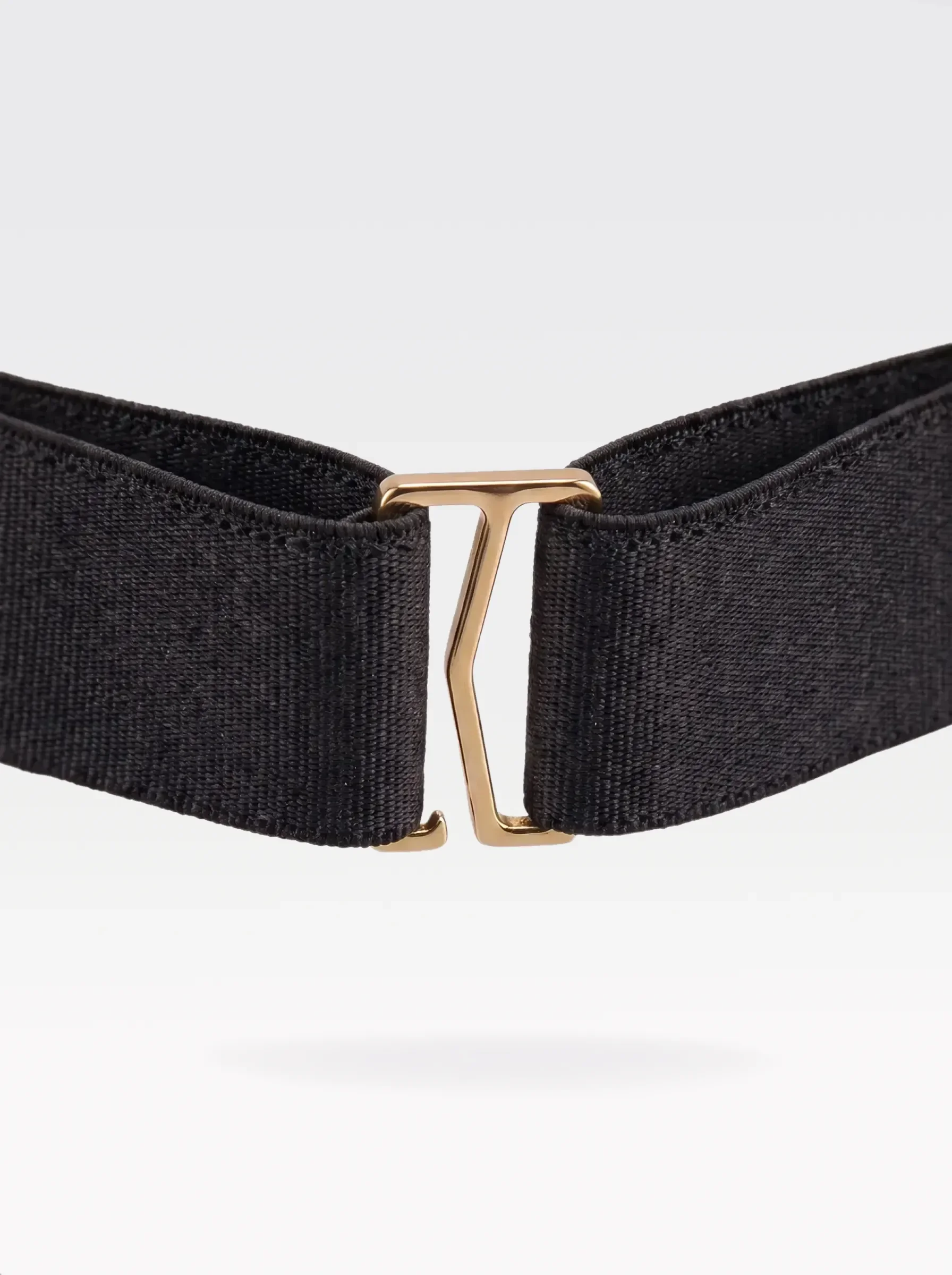 Close-up of the 24K gold-plated brass G hook closure on the black elastic band of a Sainte Sve Belt Nappa
