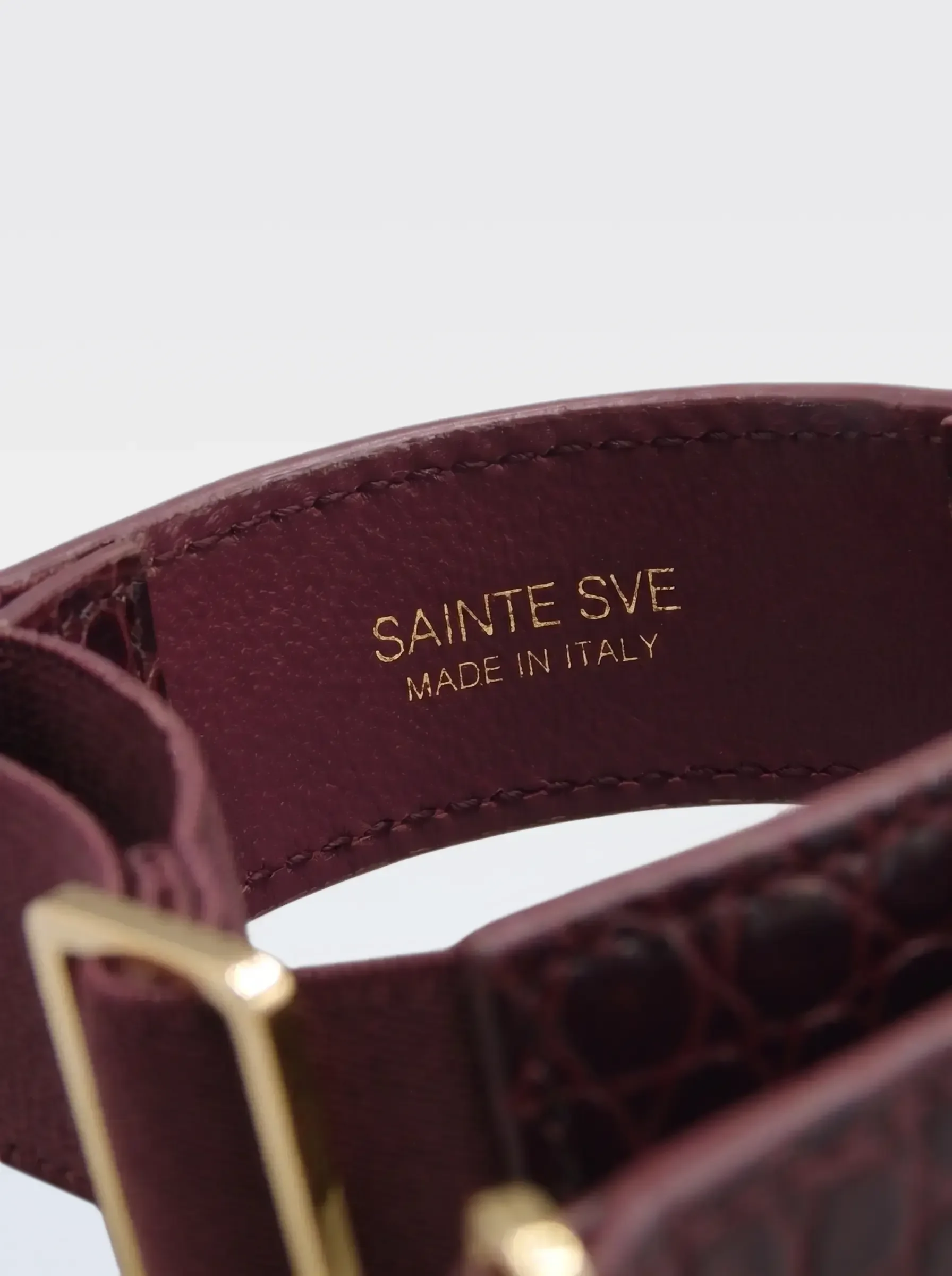 Close-up of the burgundy nappa lambskin lining of the Sainte Sve Arm Bracelets Croc with the foil-stamped Sainte Sve Made in Italy logo