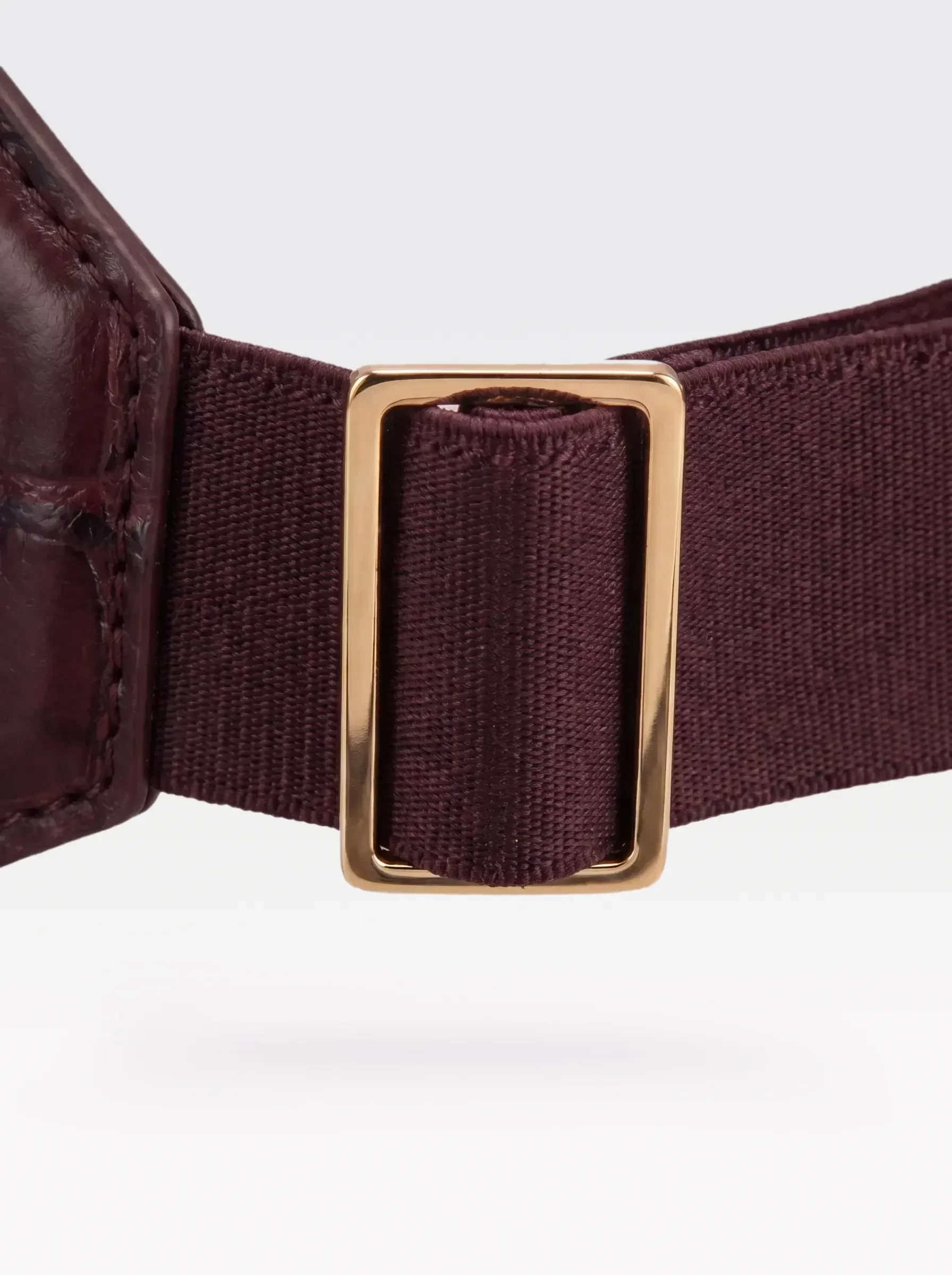 Close-up of the 24K gold-plated brass slider on the burgundy elastic band of a Sainte Sve Belt Croc