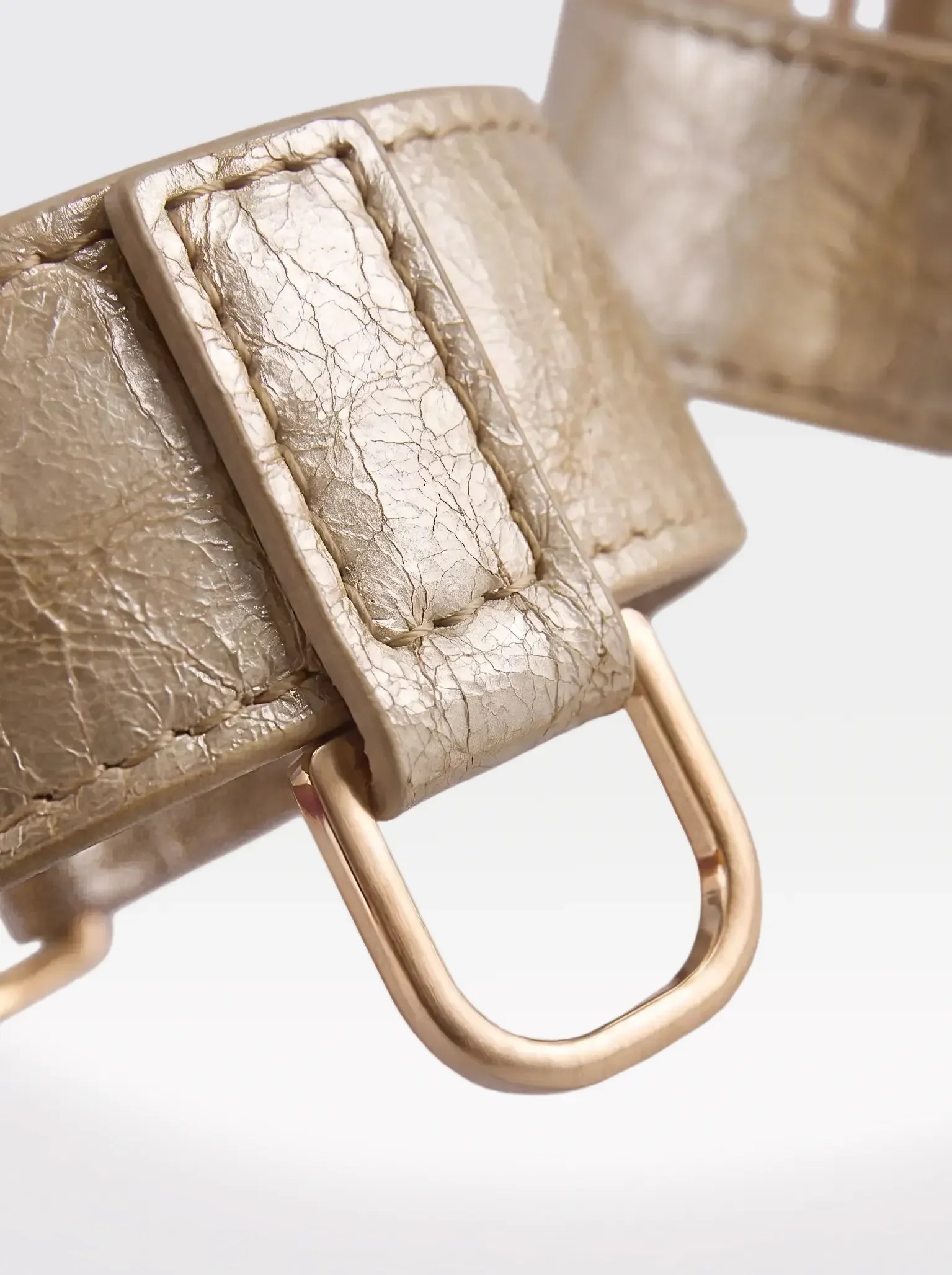Close-up of the 24K gold-plated brass D ring on a gold laminated lambskin wrist bracelet by Sainte Sve