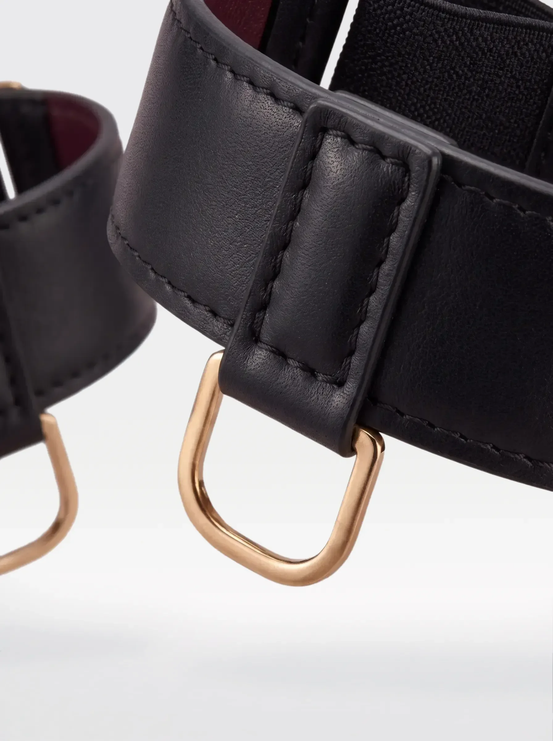 Close-up of the 24K gold-plated brass D ring on a black nappa lambskin arm bracelet by Sainte Sve