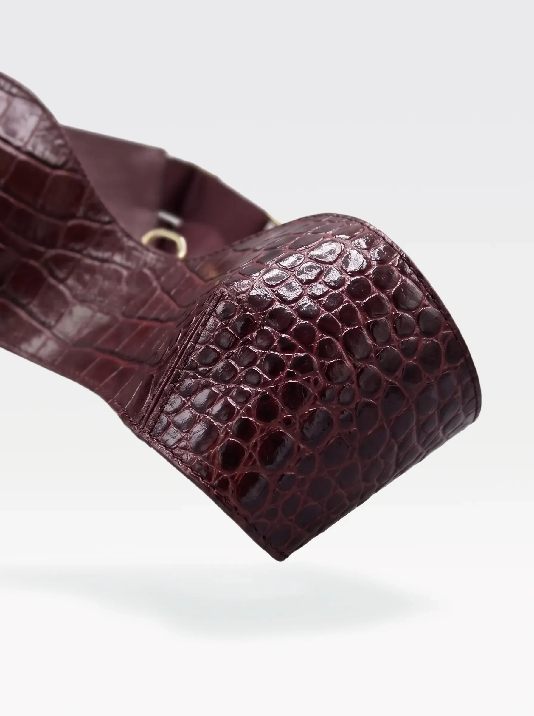 Close-up of the burgundy crocodile-embossed lambskin band with a 24K gold-plated brass eyelet of the Sainte Sve V.N.V Croc