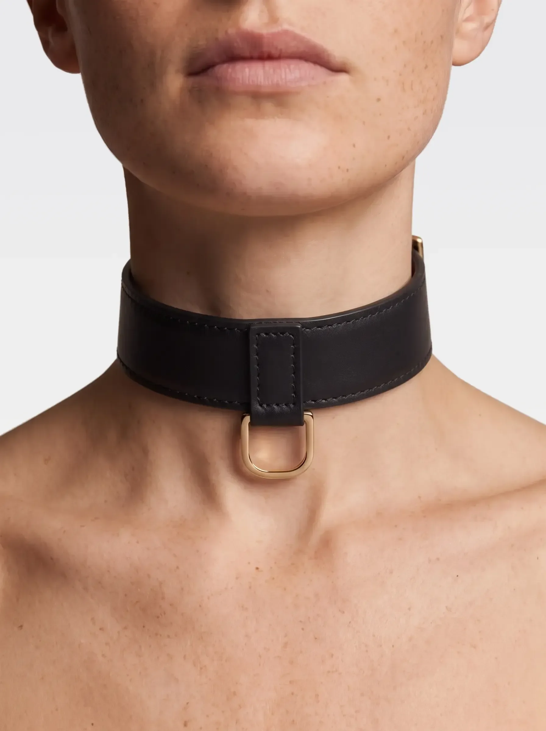 Sainte Sve Choker Nappa in black nappa lambskin with a 24K gold-plated brass D ring, worn at the neck, editorial image
