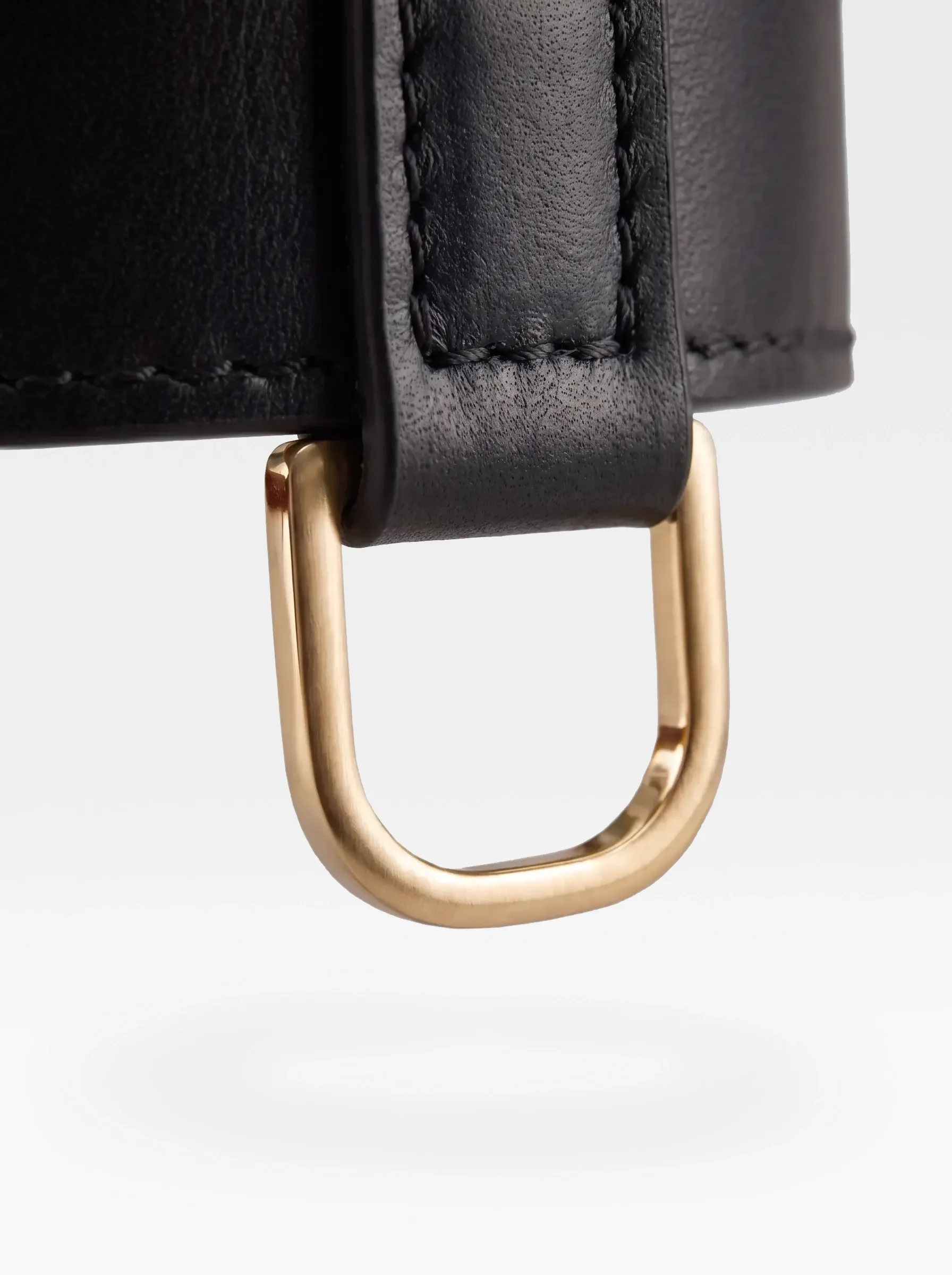 Close-up of the 24K gold-plated brass D ring on a black nappa lambskin choker by Sainte Sve
