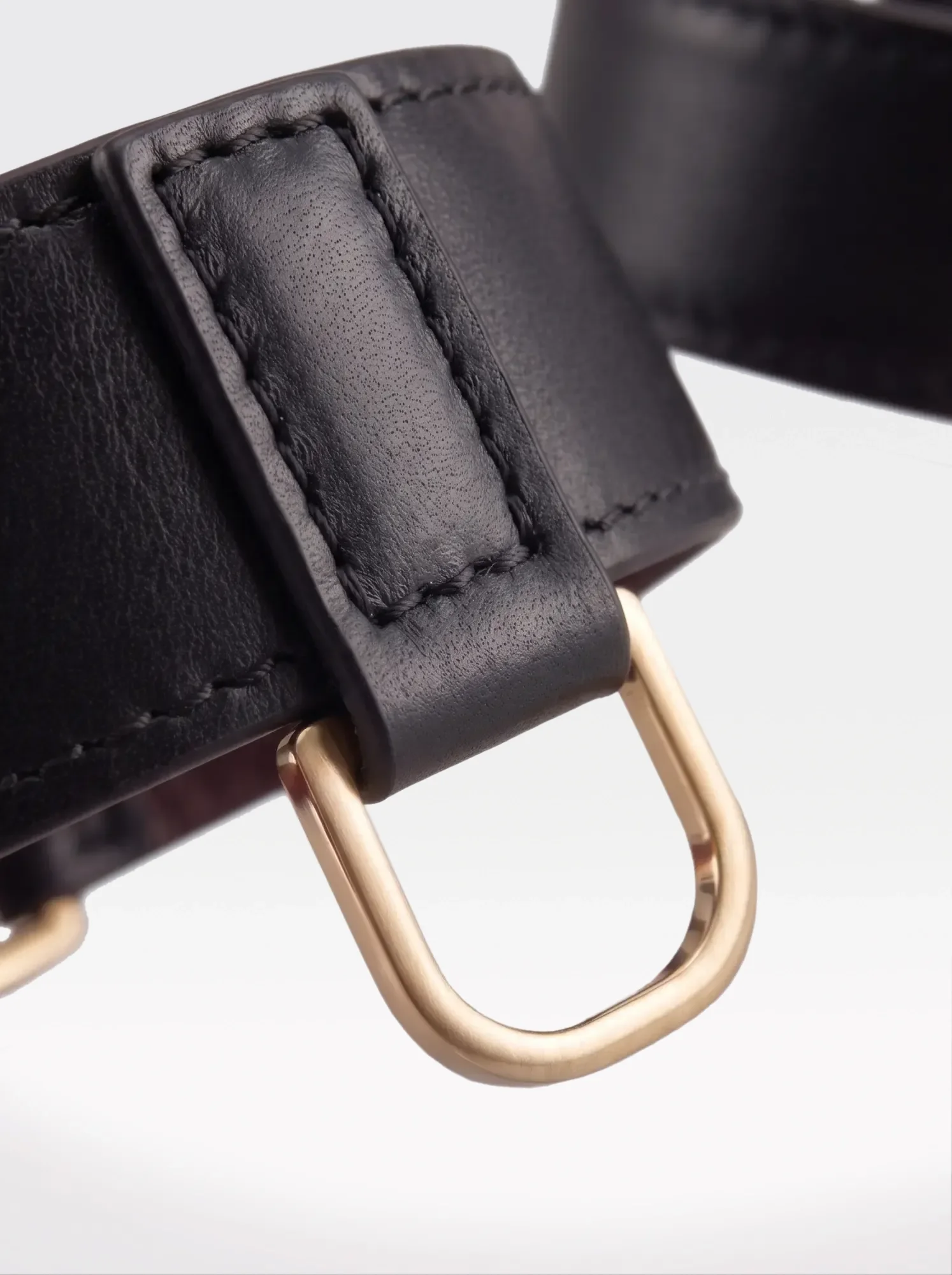 Close-up of the 24K gold-plated brass D ring on a black nappa lambskin wrist bracelet by Sainte Sve