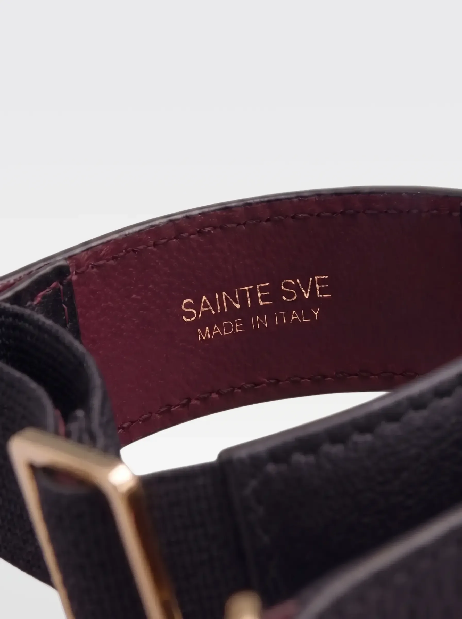 Close-up of the burgundy nappa lambskin lining of the Sainte Sve Arm Bracelets Nappa with the foil-stamped Sainte Sve Made in Italy logo