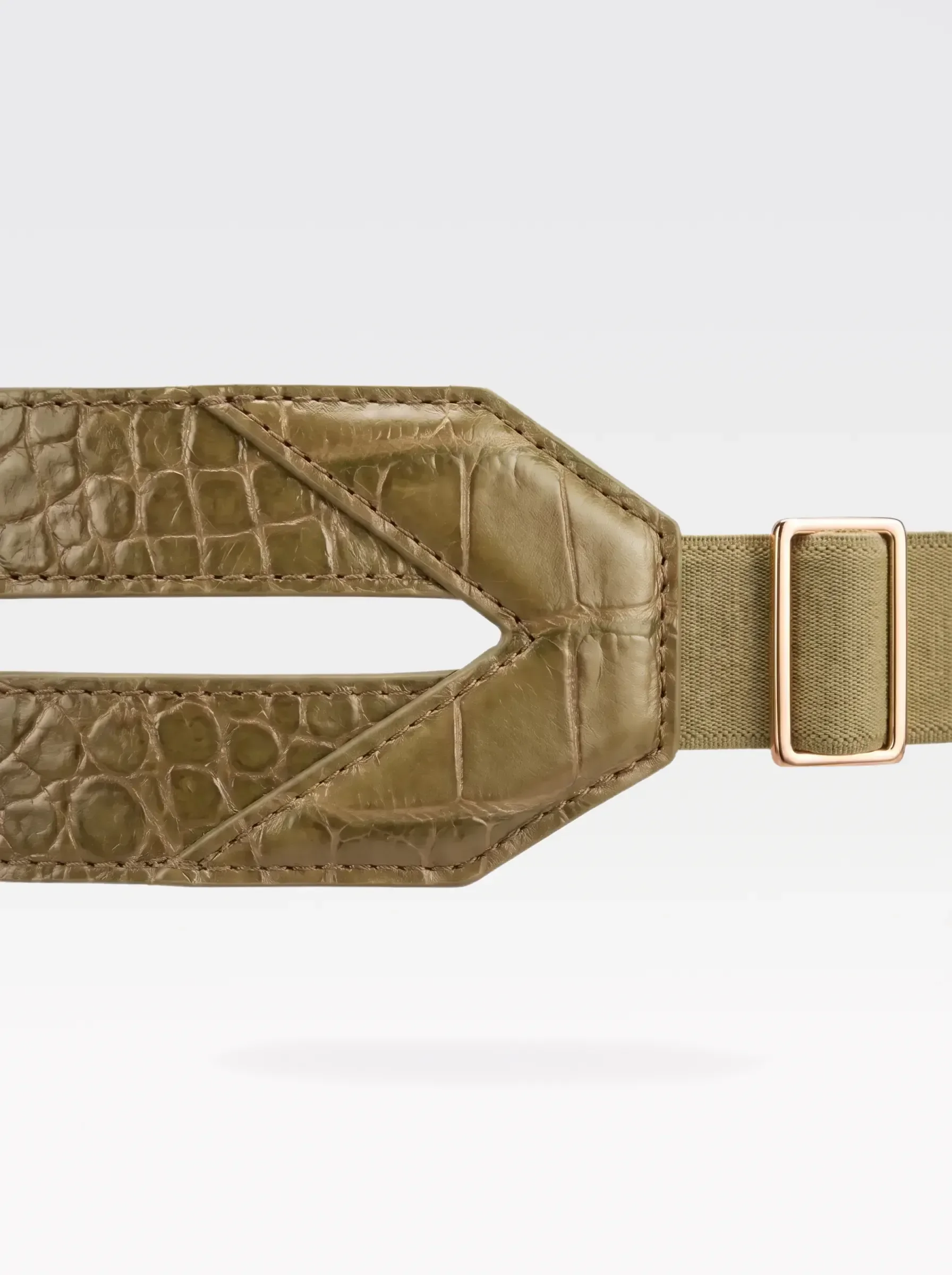 Close-up of the V-shaped pistachio crocodile-embossed lambskin panel and 24K gold-plated brass slider of the Sainte Sve Belt Croc