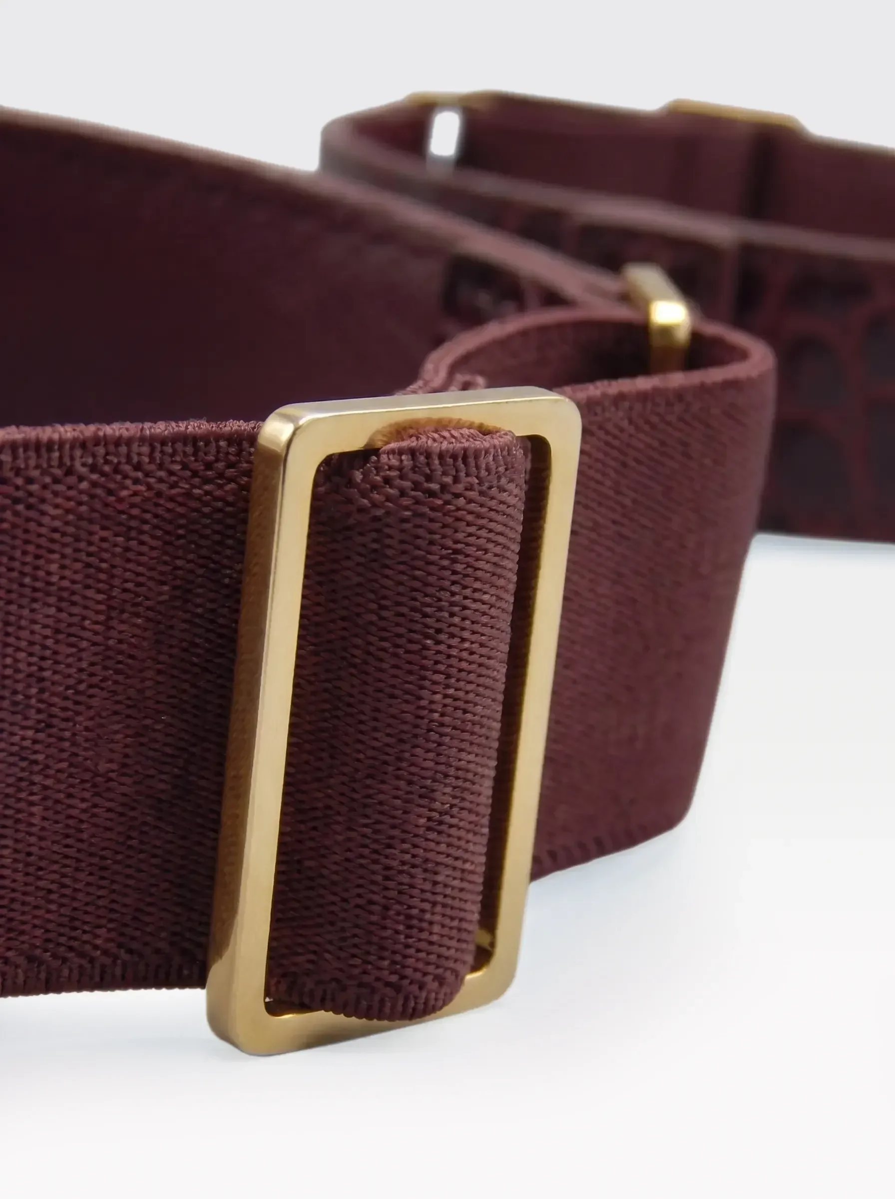 Close-up of the 24K gold-plated brass slider on the burgundy elastic band of a Sainte Sve Arm Bracelets Croc