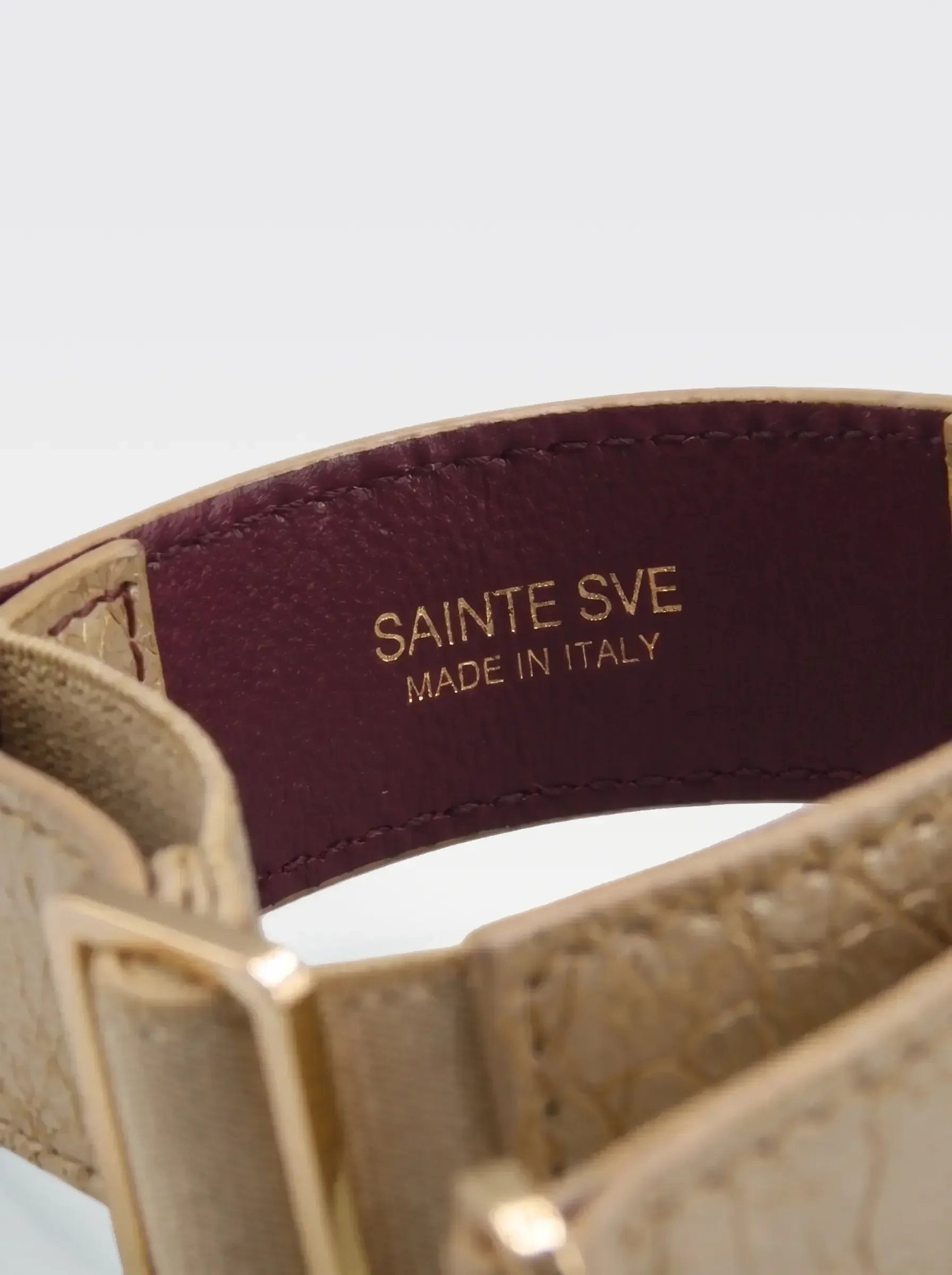 Close-up of the burgundy nappa lambskin lining of the Sainte Sve Arm Bracelets Laminated with the foil-stamped Sainte Sve Made in Italy logo