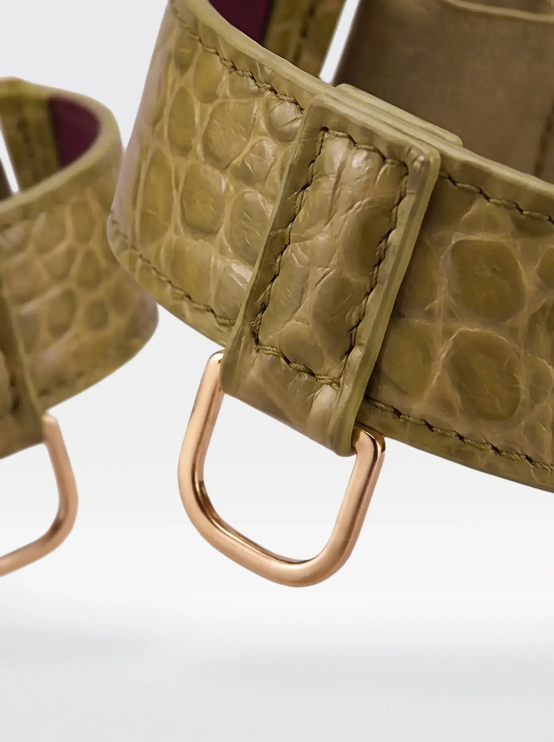 Close-up of the 24K gold-plated brass D ring on a pistachio crocodile-embossed lambskin arm bracelet by Sainte Sve