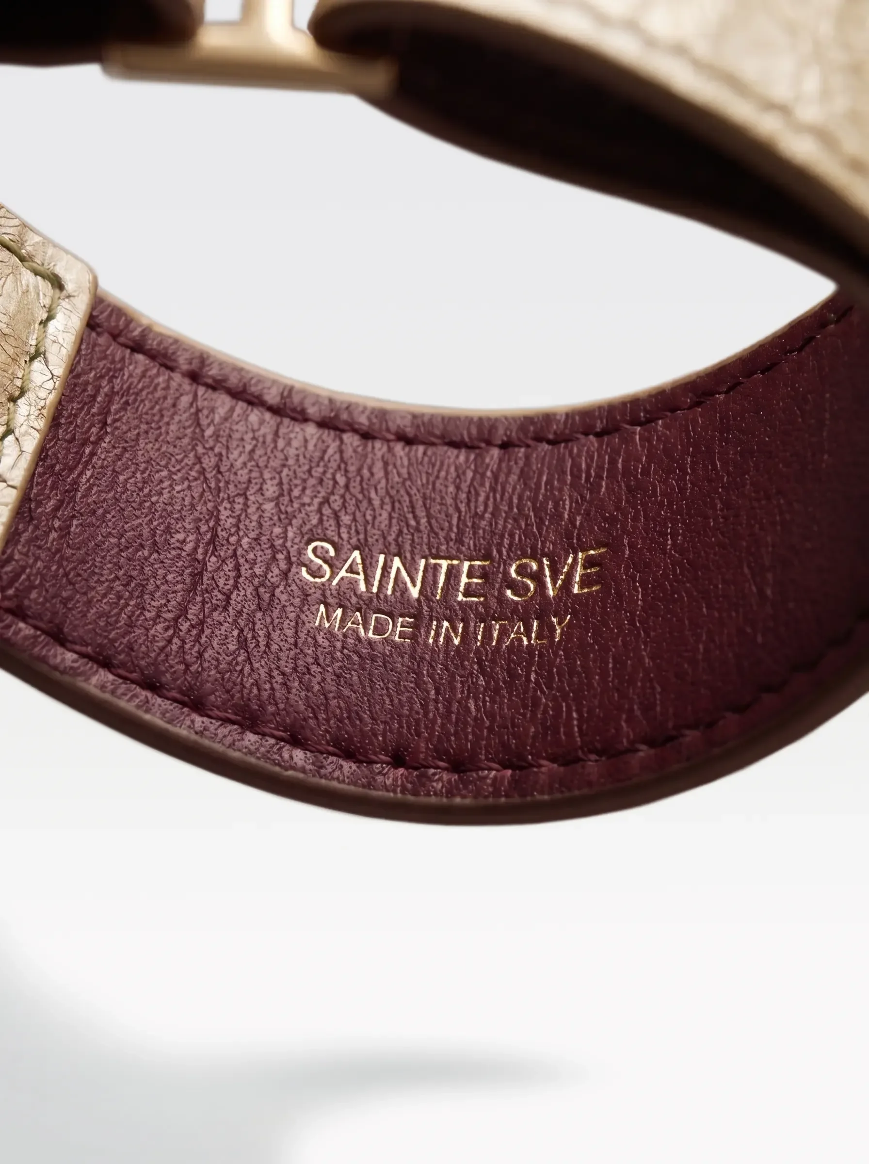 Close-up of the burgundy nappa lambskin lining of the Sainte Sve Choker Laminated with the foil-stamped Sainte Sve Made in Italy logo