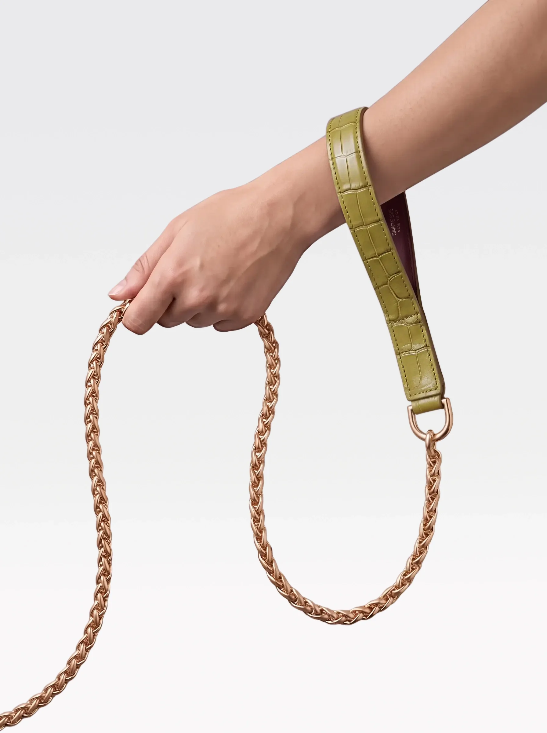Sainte Sve Leash Croc with a pistachio crocodile-embossed lambskin handle and a 24K gold-plated brass Spiga chain, held in hand, editorial image