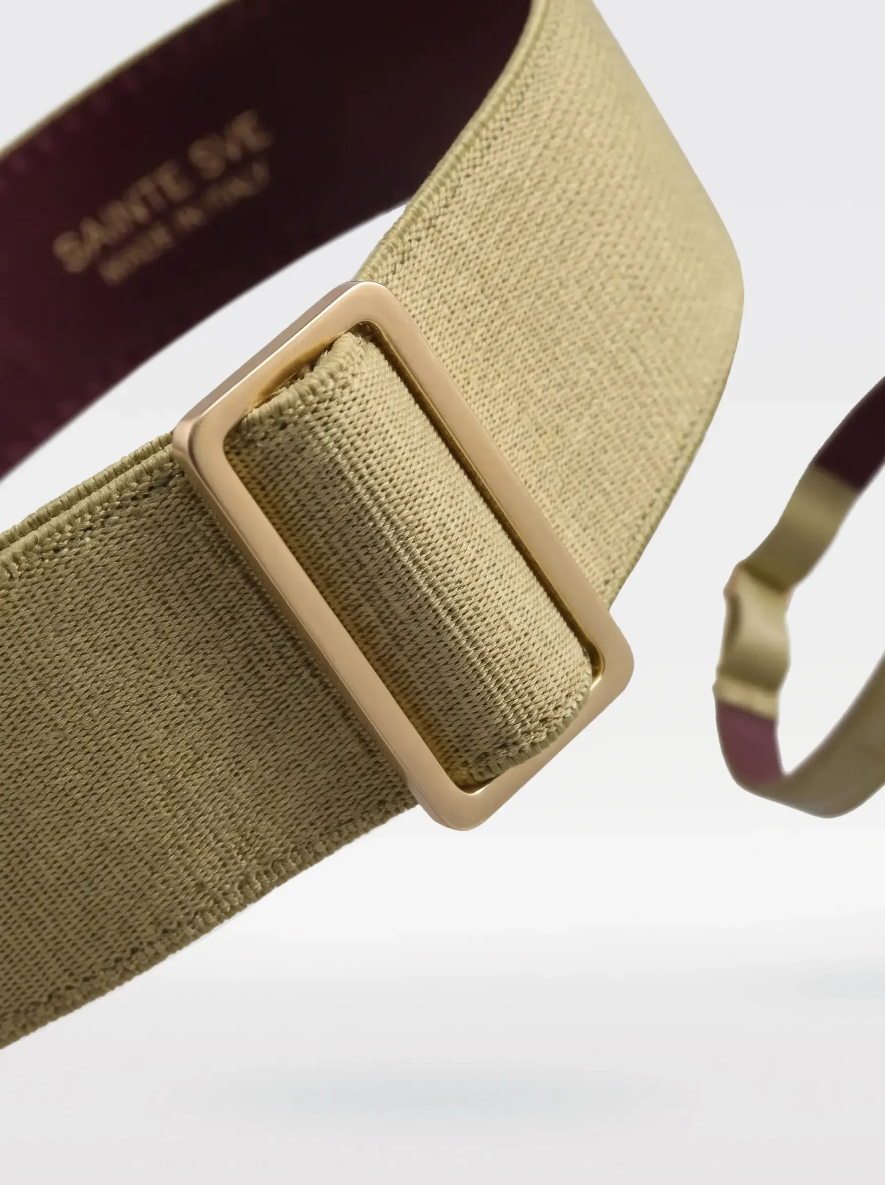 Close-up of the 24K gold-plated brass slider on the pistachio elastic band of a Sainte Sve Garters Croc