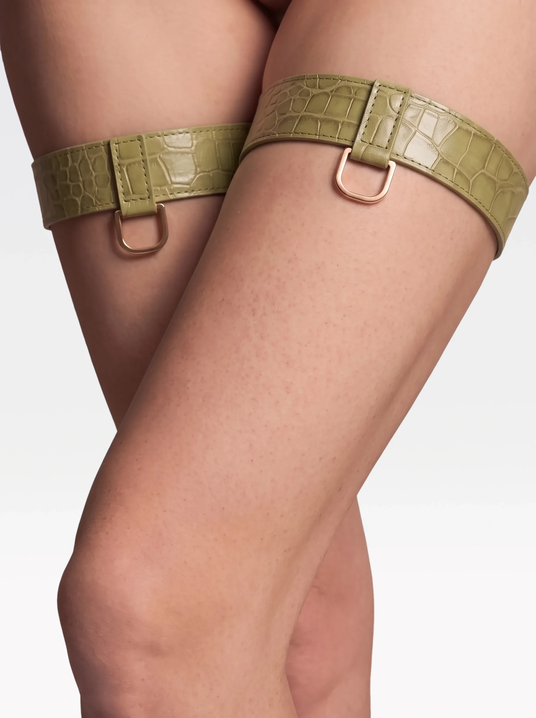 Sainte Sve Garters Croc in pistachio crocodile-embossed lambskin with 24K gold-plated brass D rings, worn on the thighs, editorial image