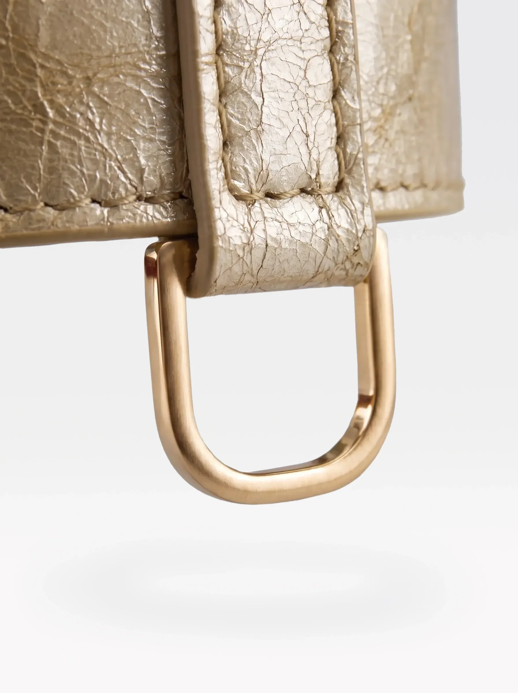 Close-up of the 24K gold-plated brass D ring on a gold laminated lambskin choker by Sainte Sve