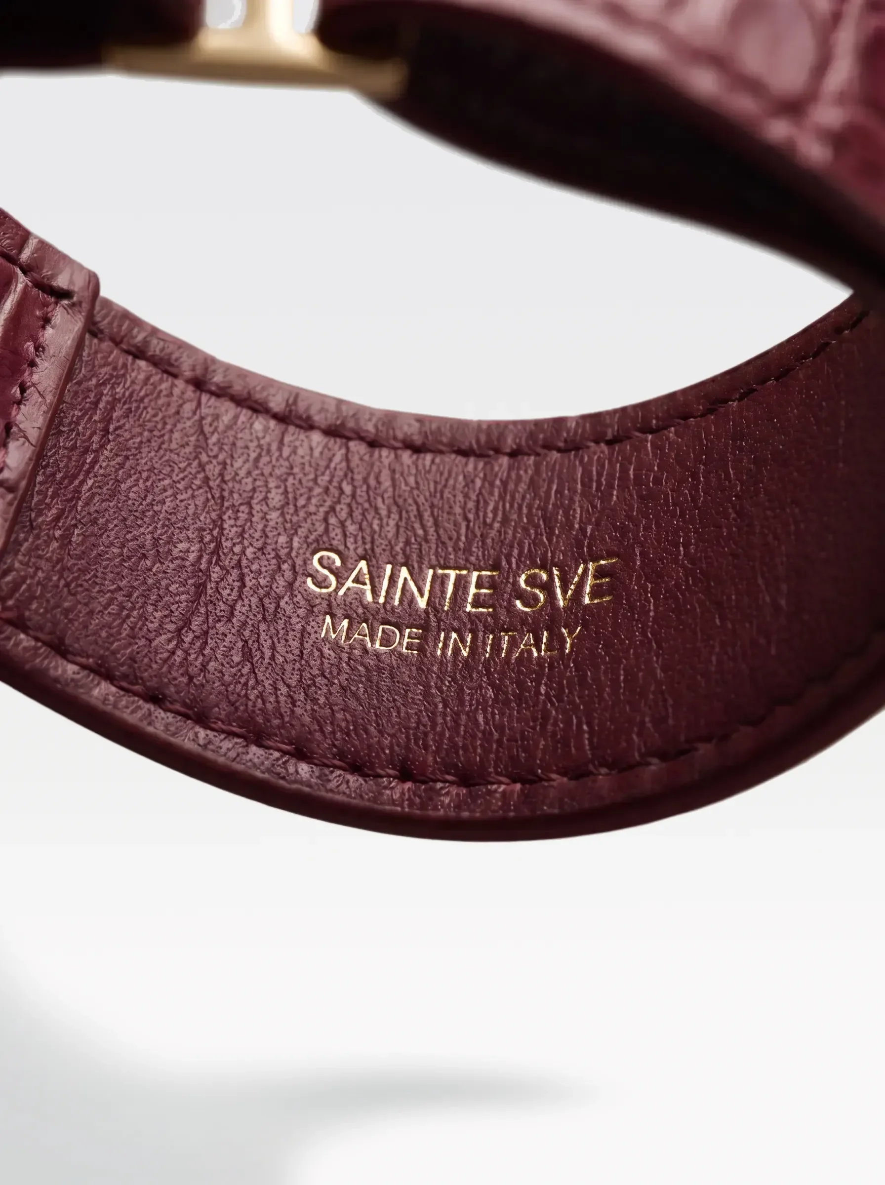 Close-up of the burgundy nappa lambskin lining of the Sainte Sve Choker Croc with the foil-stamped Sainte Sve Made in Italy logo