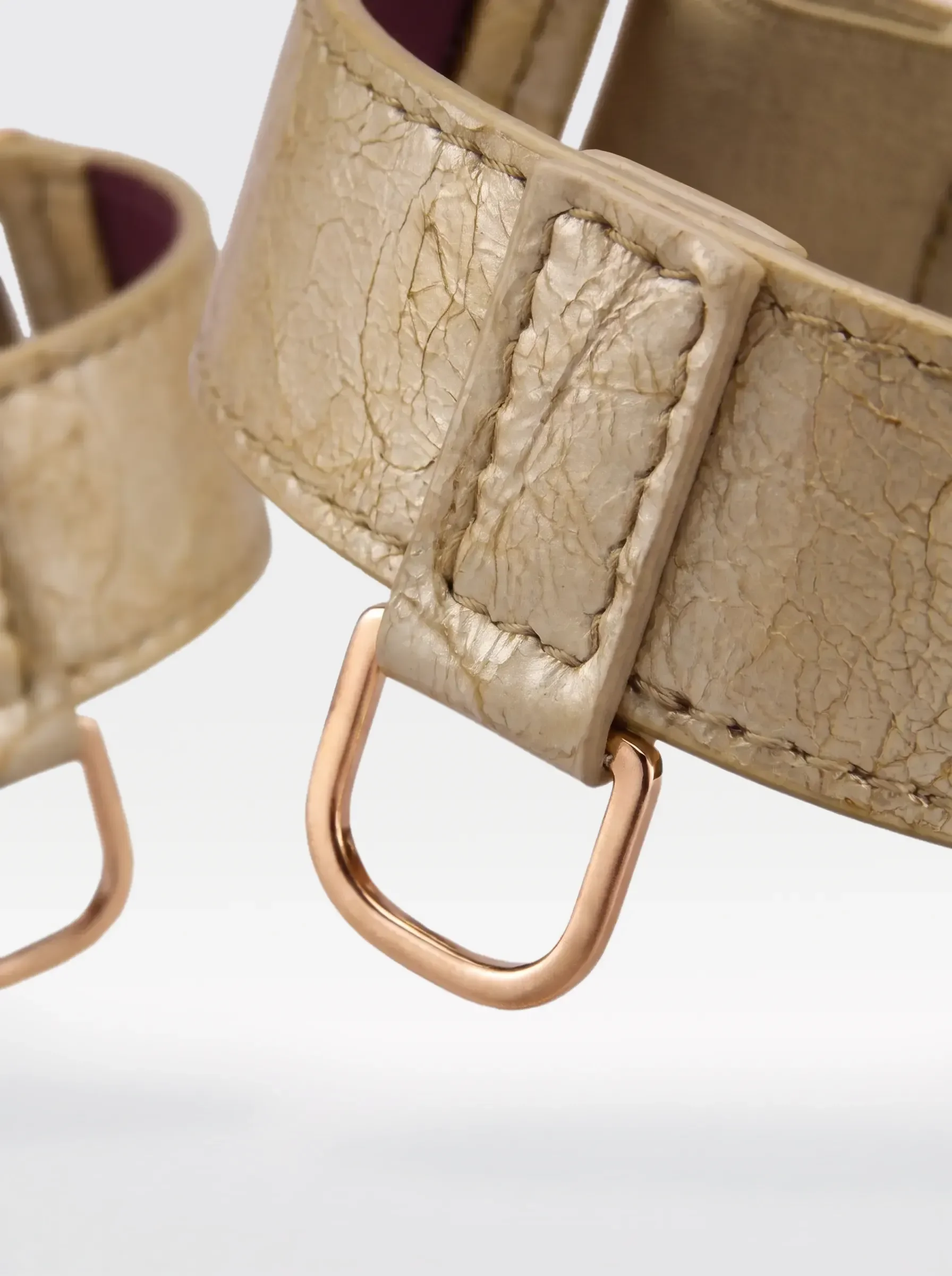 Close-up of the 24K gold-plated brass D ring on a gold laminated lambskin arm bracelet by Sainte Sve