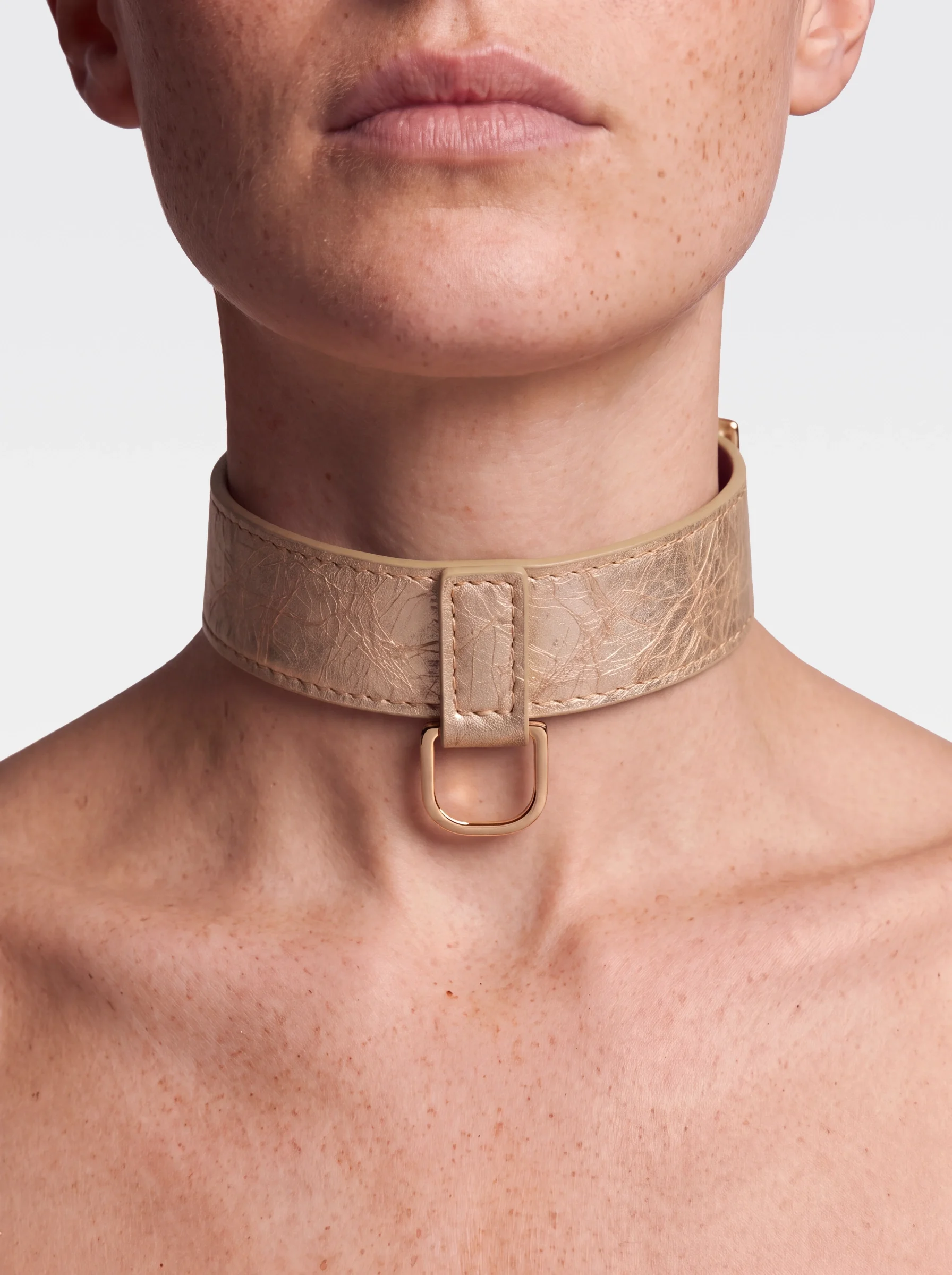 Sainte Sve Choker Laminated in gold laminated lambskin with a 24K gold-plated brass D ring, worn at the neck, editorial image