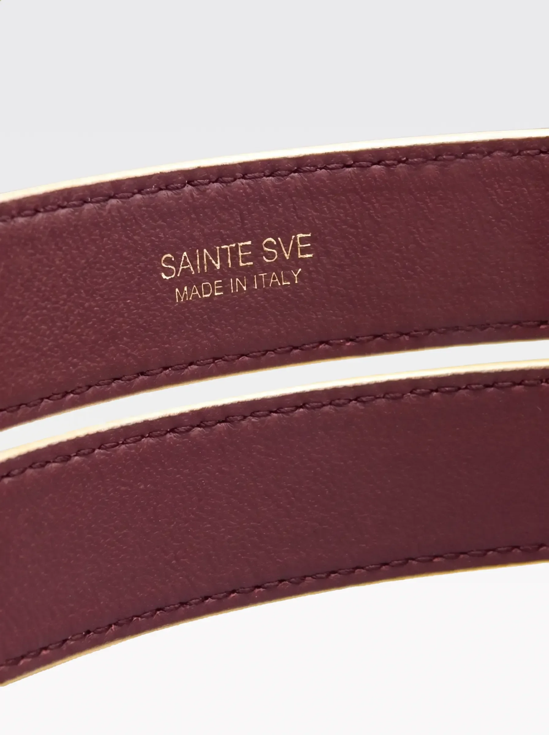 Close-up of the burgundy nappa lambskin lining of the Sainte Sve Belt Laminated with the foil-stamped Sainte Sve Made in Italy logo