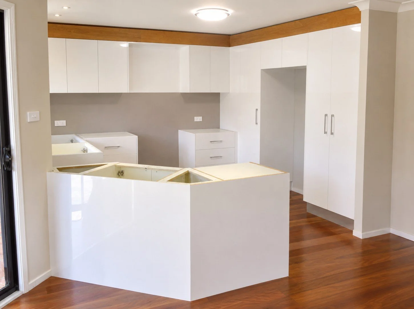 Custom kitchen renovation with white joinery and timber floor .