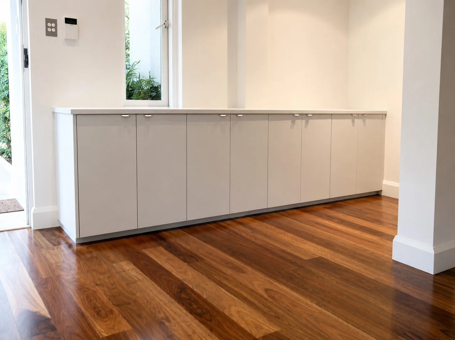 Custom built-in entry joinery with white cabinetry and wooden flooring.