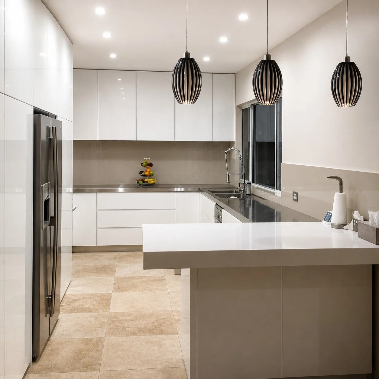 Custom white kitchen with stainless steel benchtops, integrated appliance and pendant lighting.
