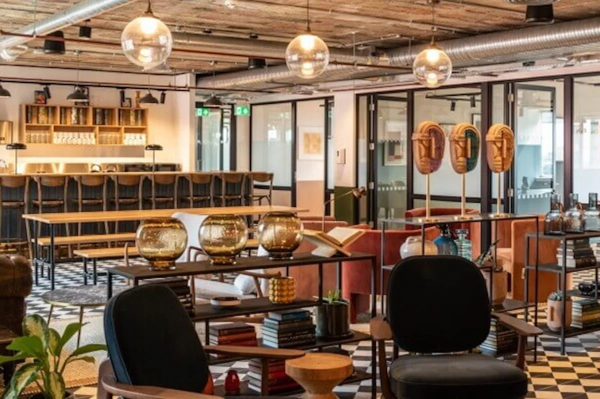 Modern, stylish interior of a cafe or lounge with wooden accents, patterned black-and-white checkered flooring, decorative objects, and seating areas.
