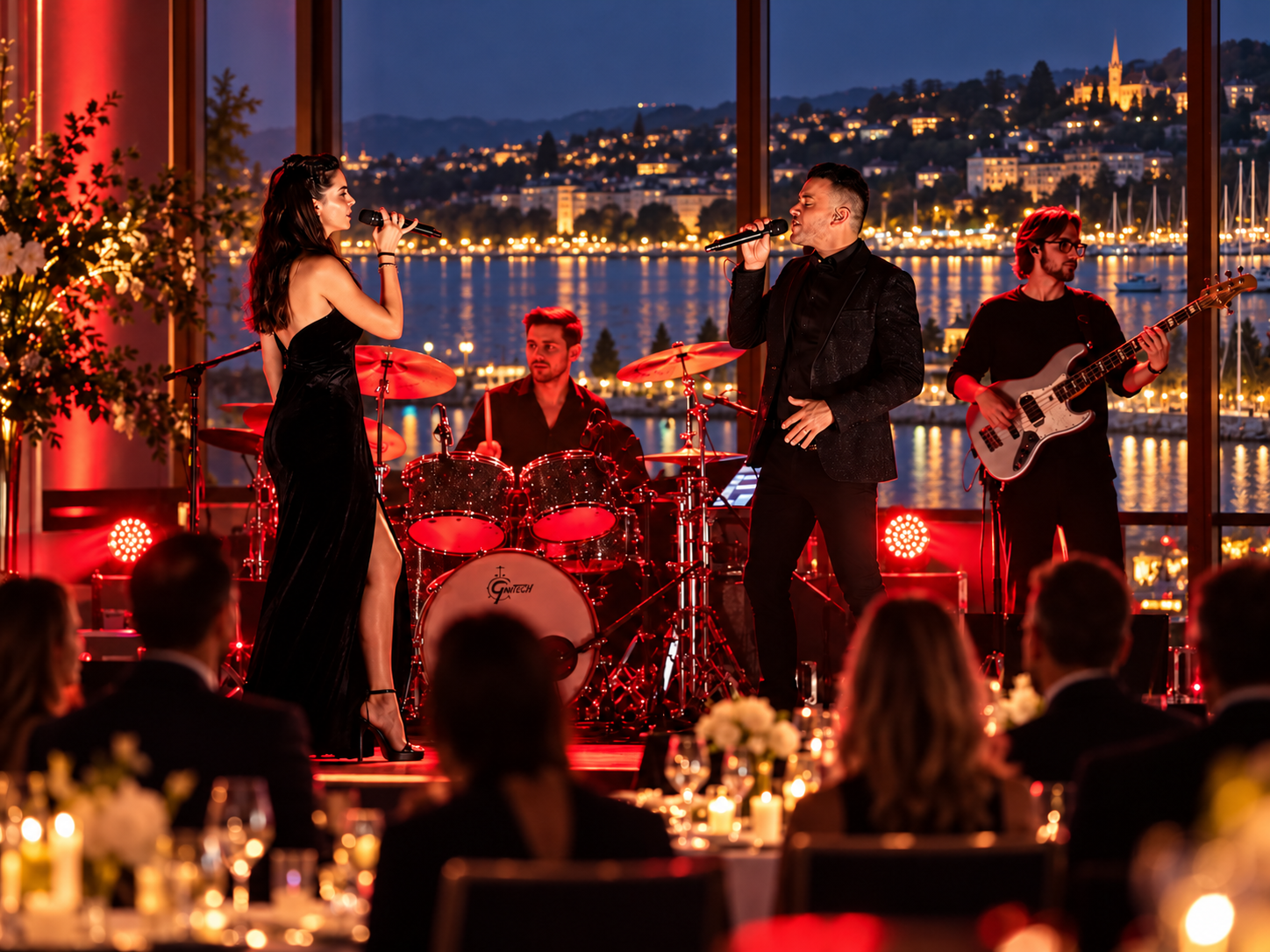 Groupe de musiciens en performance lors d'un concert pour une entreprise avec un décor de nuit en arrière-plan, comprenant un lac, des batiments éclairés et une église, dans une salle avec vue panoramique sur lausanne.