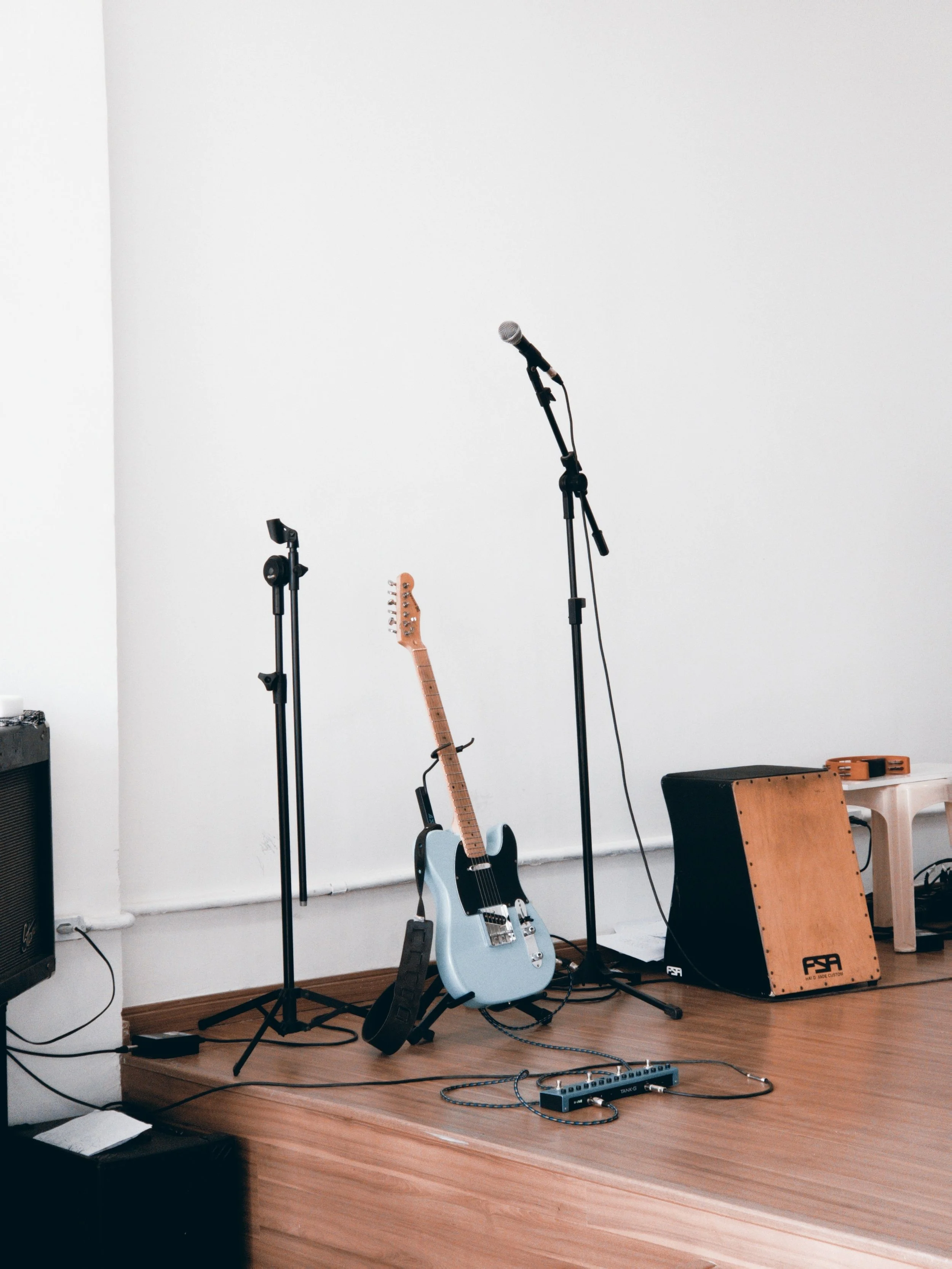 Une scène de scène de musique avec une guitare électrique, un micro, un ampli, et un instrument de percussion, prêt pour une performance.