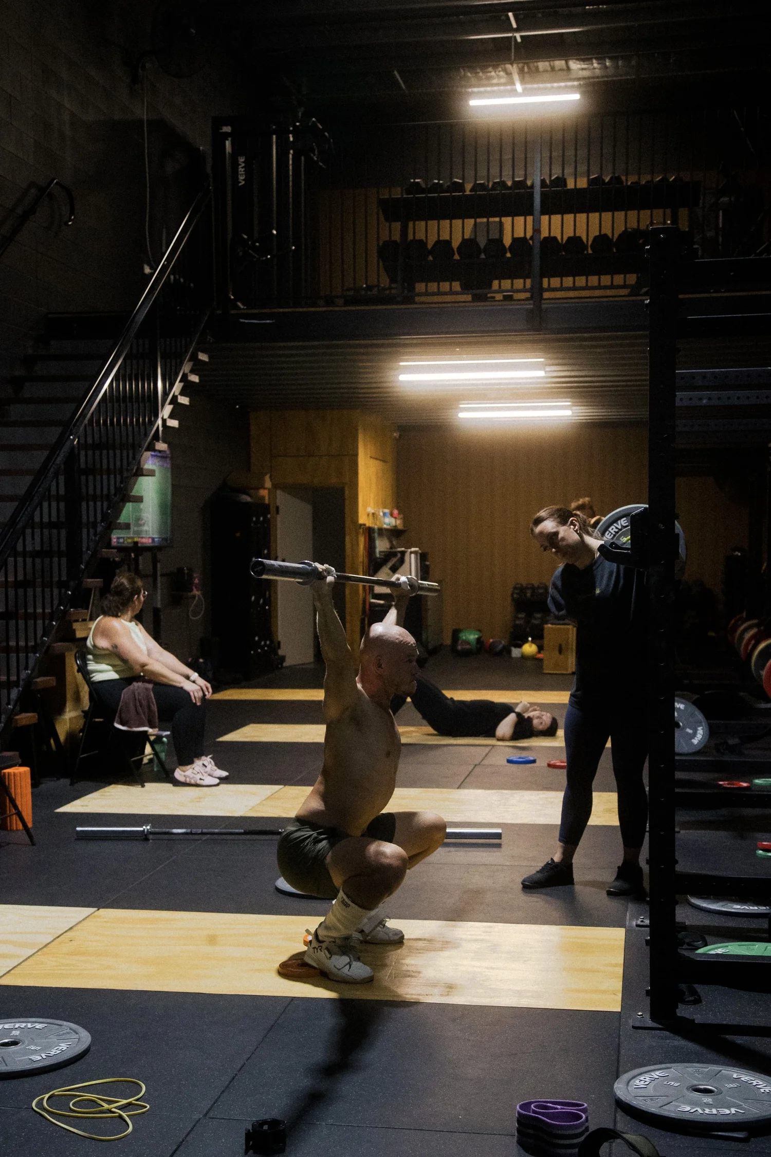 Coach observing a weightlifter in an overhead squat