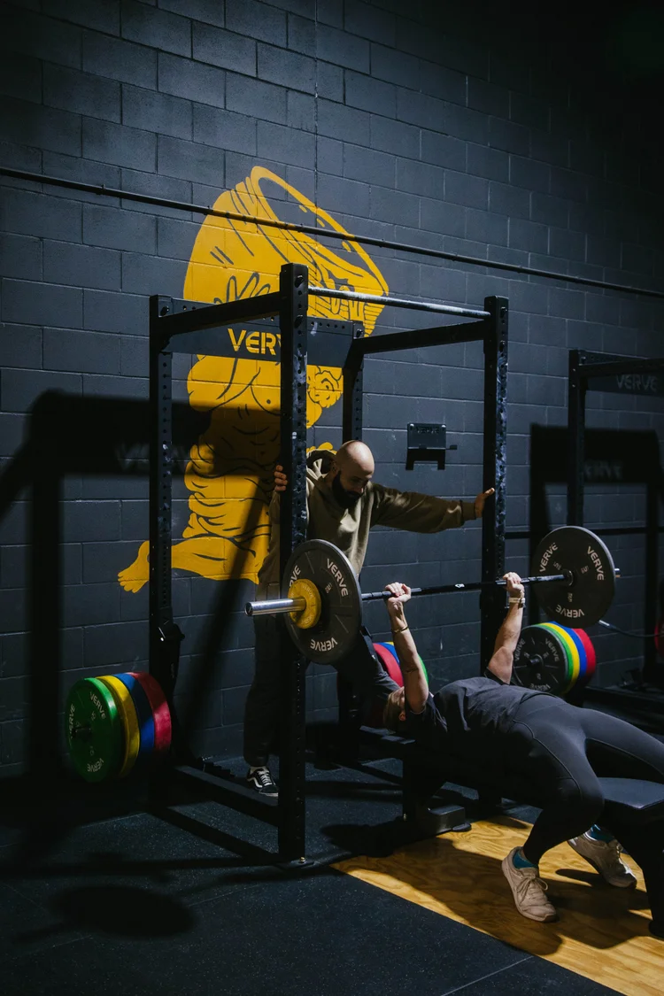 Coach working with a member on bench press technique at Crucible Strength