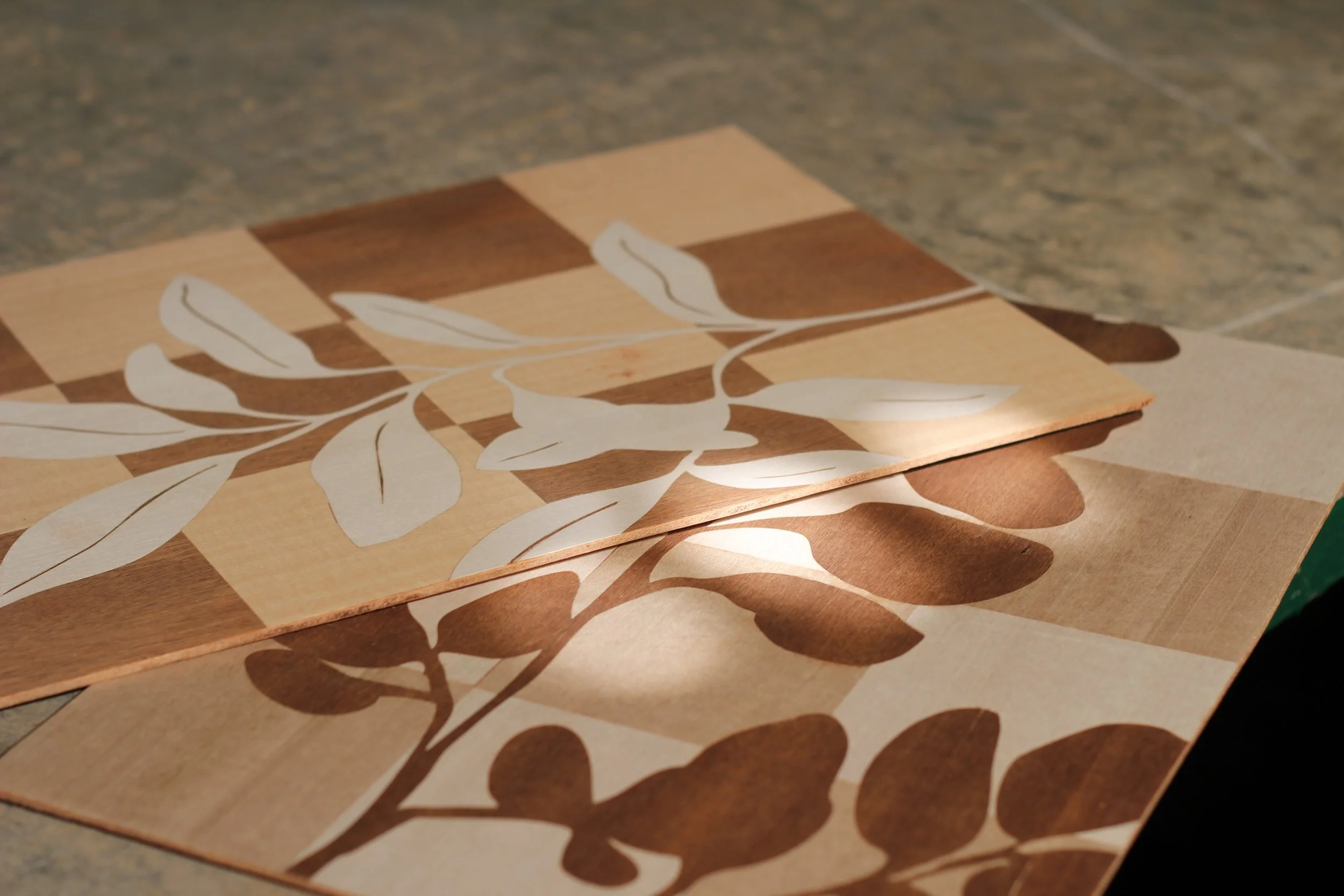 A decorative wooden chessboard with white floral and botanical patterns overlay.