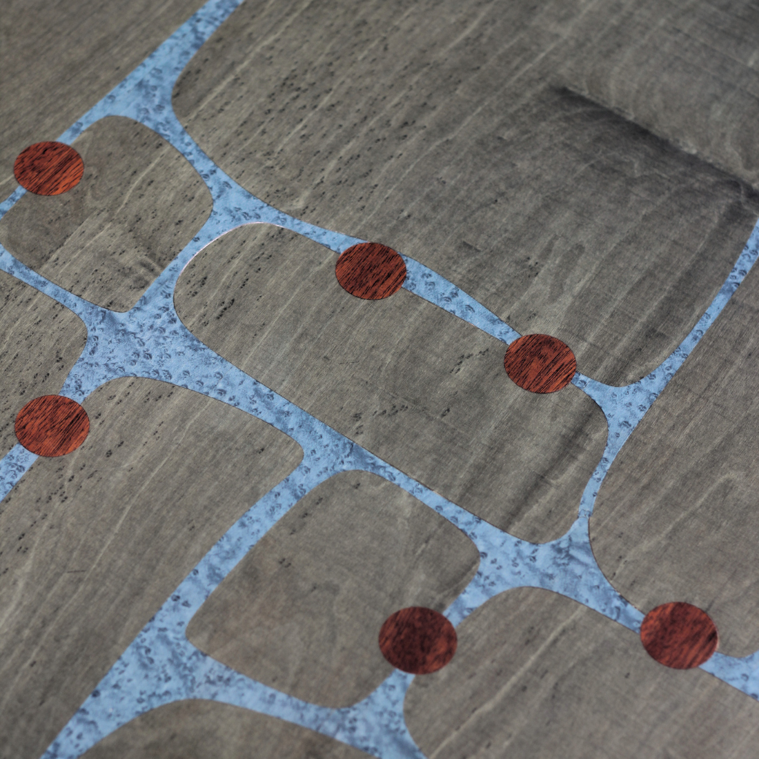 Close-up of a circuit board with gray pathways, red circular connection points, and a textured blue background.