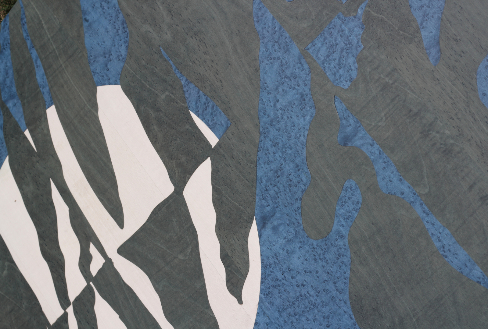 Close-up of a painted abstract design on a surface, featuring organic shapes in shades of blue, gray, and white.