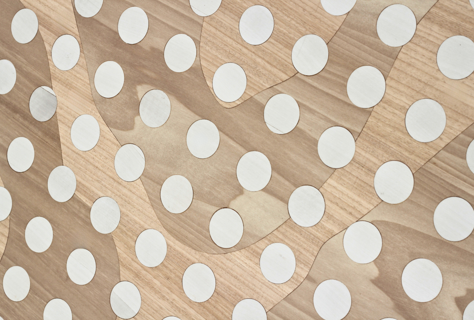 Close-up of a wooden puzzle with white circular pieces embedded into the surface.
