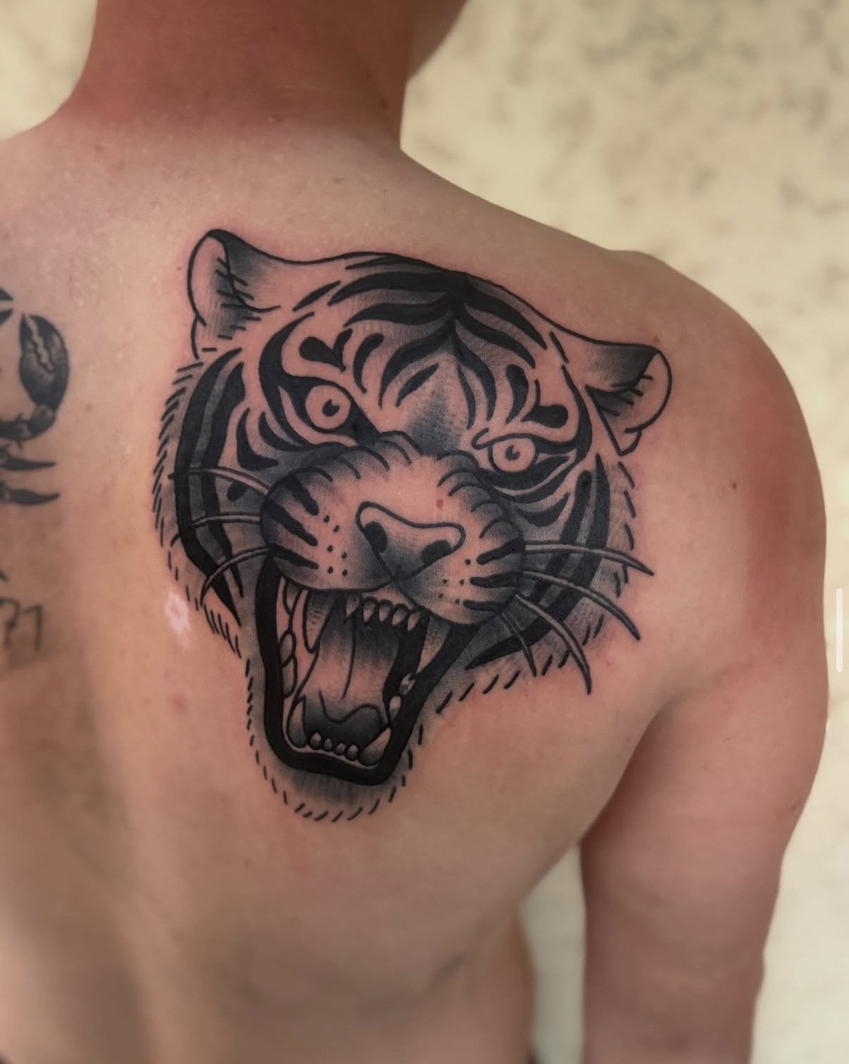 Tattoo eines aufgestürzten Tigers im schwarzen Stil auf der linken Brust des Mannes.