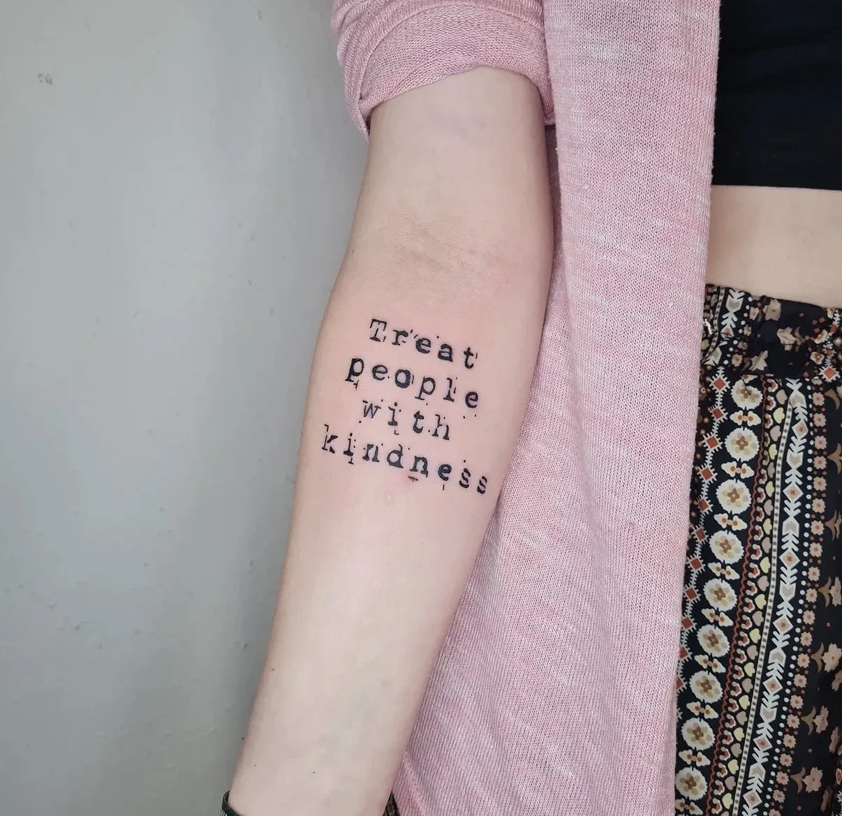 Tattoo am inneren Oberarm mit dem Text 'Treat people with kindness'