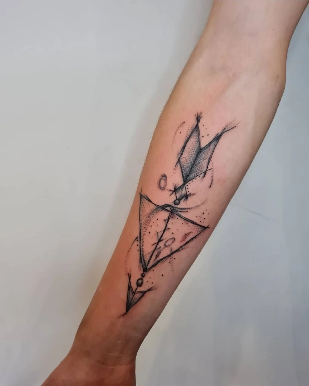 Schwarze geometrische Tattoo auf dem Unterarm, bestehend aus Linien, Punkten und Flächen, die ein abstraktes Muster bilden.