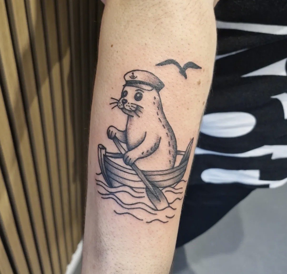 Tattoo eines Otters im Piratenkostüm auf einem Boot mit Wasser und fliegenden Vögeln