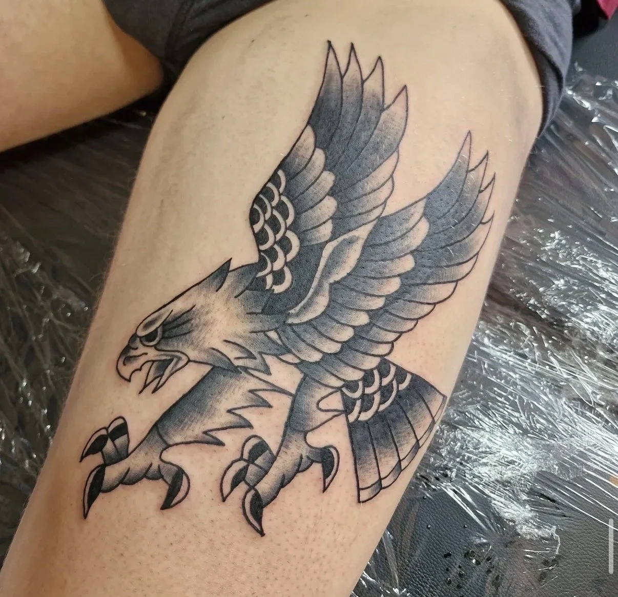 Tattoo eines kämpfenden Adlers in Schwarz auf Bein.