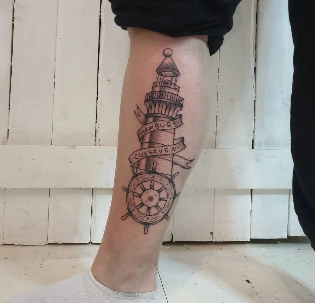 Tattoo eines Leuchtturms mit einer Schiffskelle am Fußgelenk. Die Flagge zeigt die Schriftarten: Hamburg, Cuxhaven.