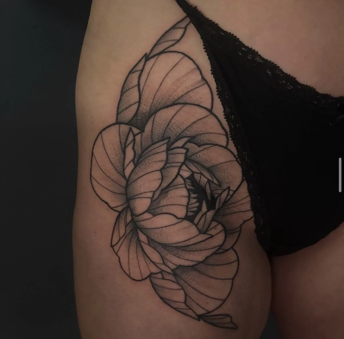 Schwarz-weiß Tattoo eines Blumenmusters auf dem Oberarm einer Person.