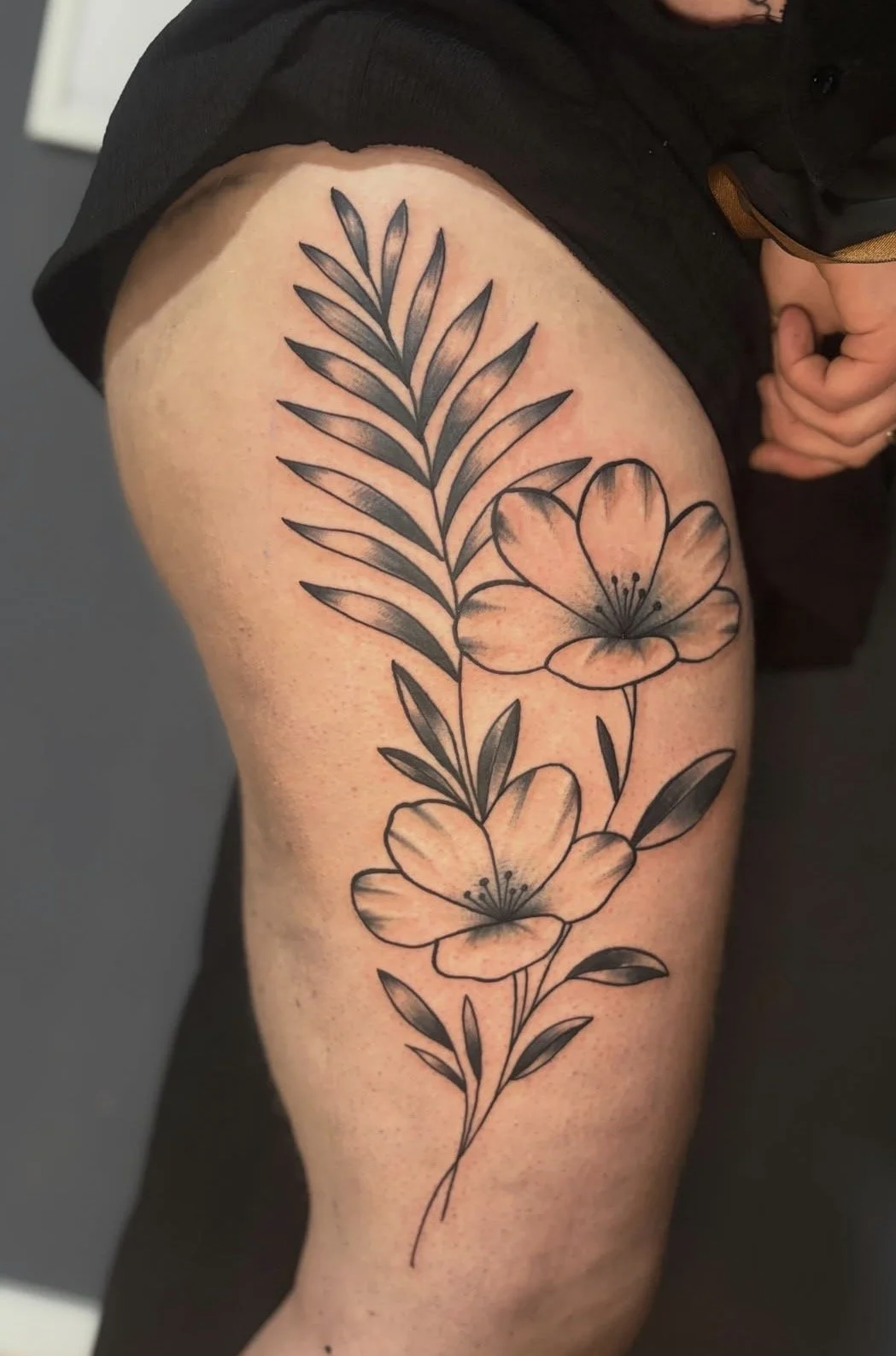 Schwarze und graue Blumentattoos mit Blüten und Blättern auf der Oberschenkel