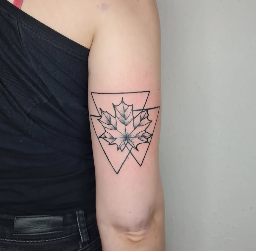 Tattoo eines Ahornblattes in geometrischem Stil auf dem Oberarm.