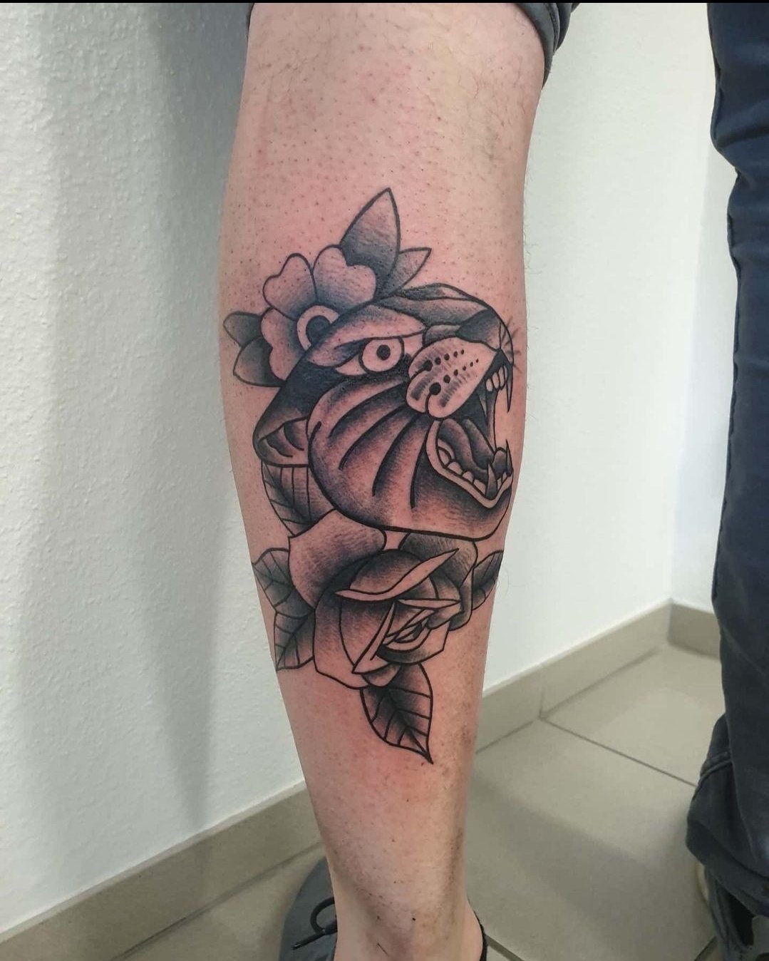 Tattoo eines Tigers, umgeben von Rosen auf dem Unterschenkel.