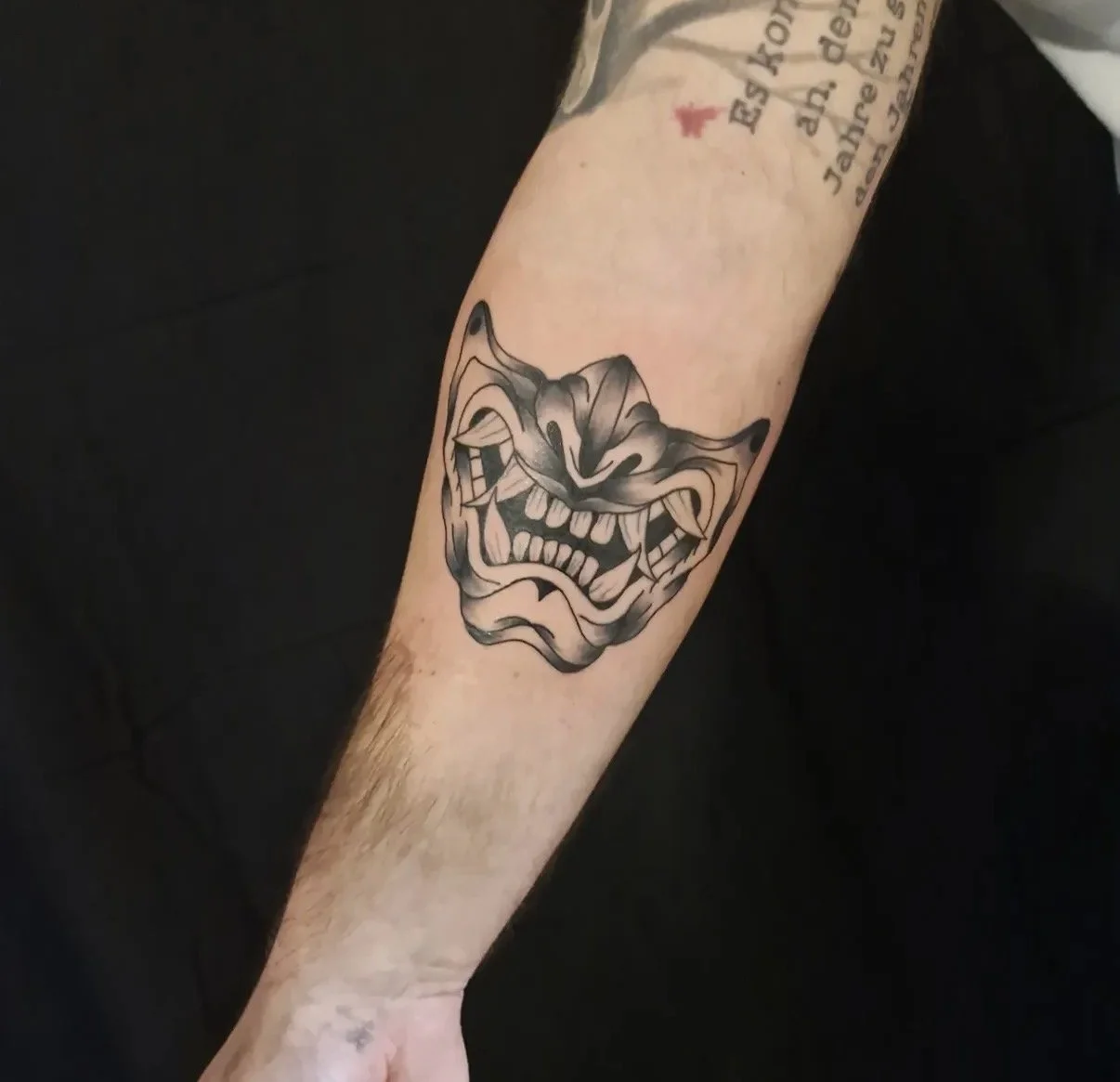 Schwarzes, grimassierendes Tier-Design-Tattoo auf dem Unterarm.